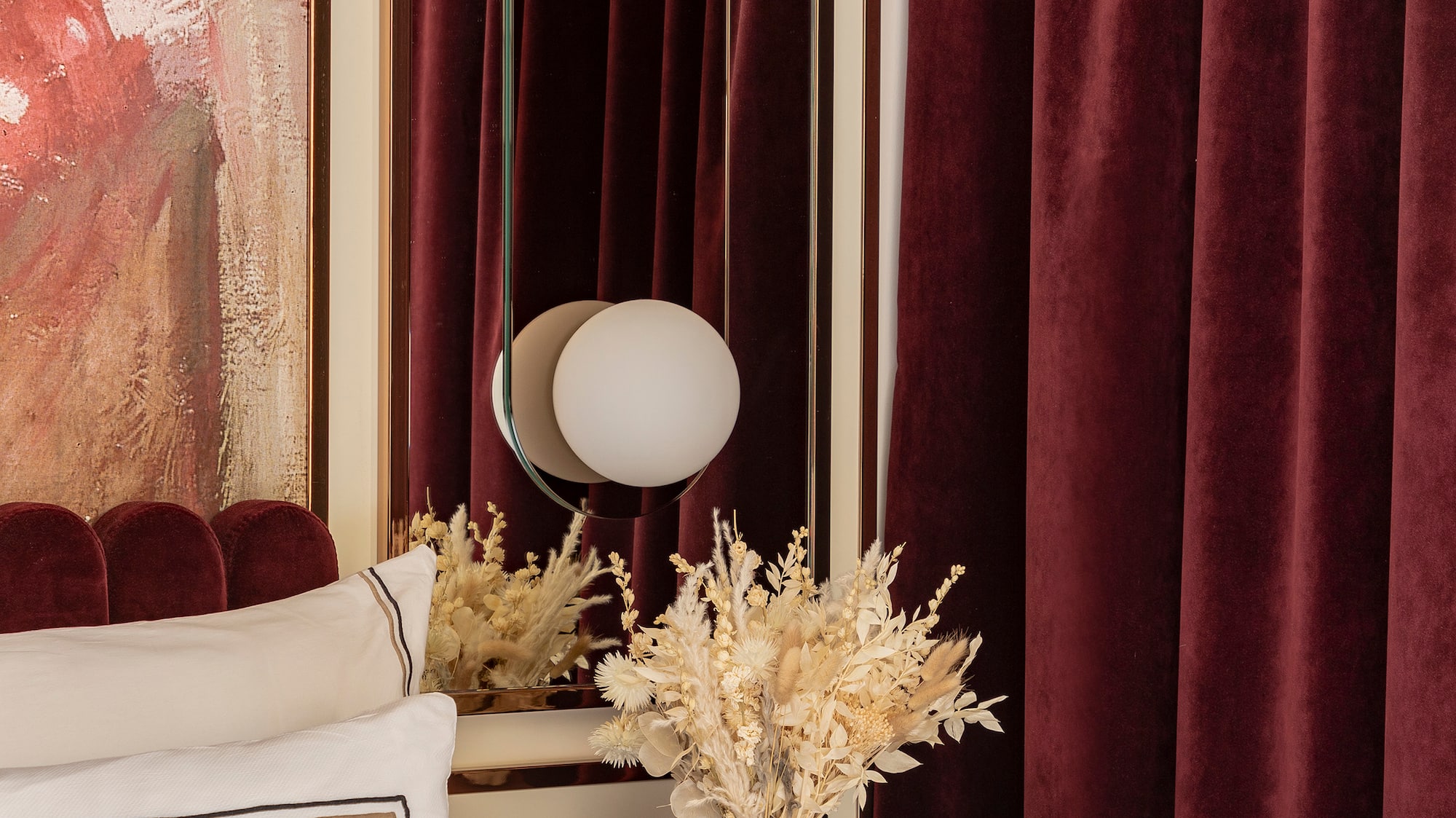 a vase of dried flowers on a table next to a mirror