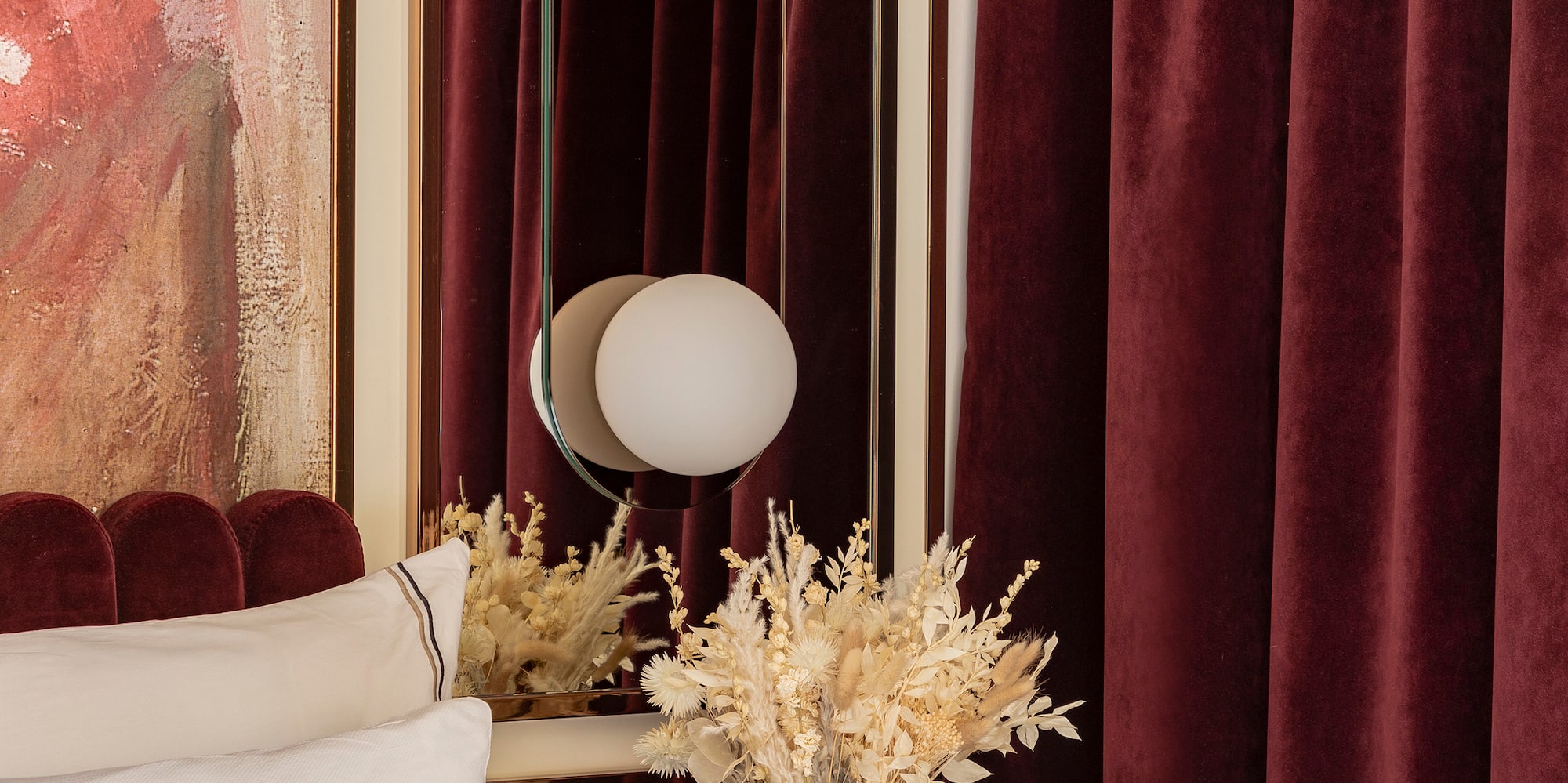 a vase of dried flowers on a table next to a mirror
