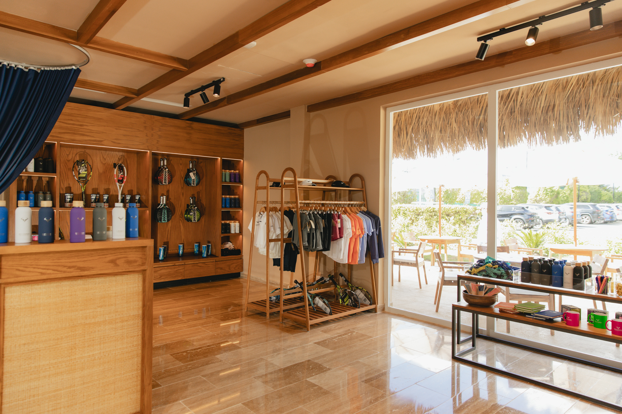 Modern shop interior: tennis rackets, sportswear, colorful bottles, wooden shelves.