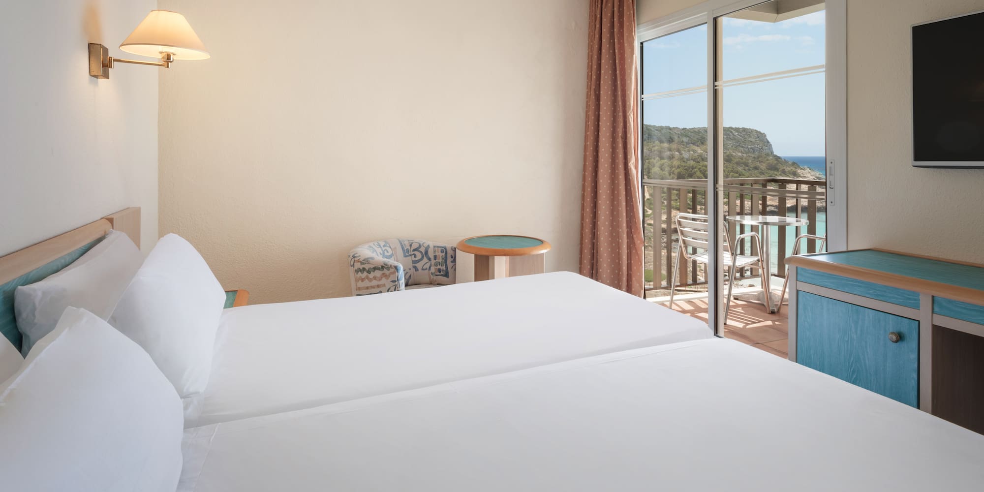 a room with two beds and a balcony overlooking the ocean