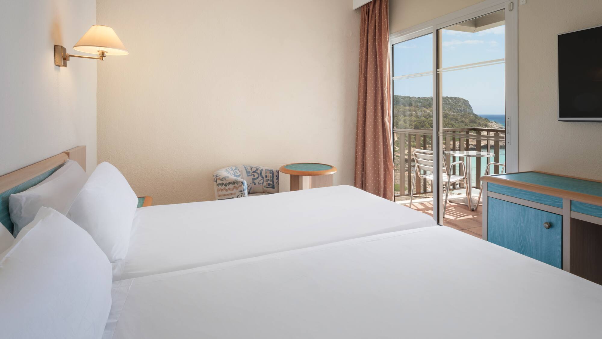 a room with two beds and a balcony overlooking the ocean