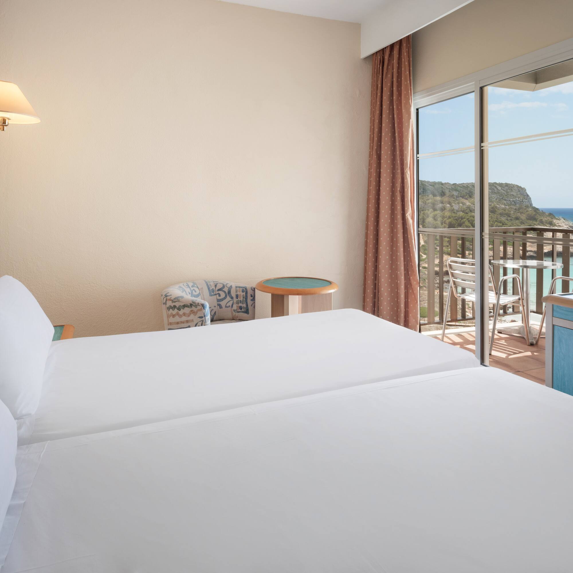 a room with two beds and a balcony overlooking the ocean