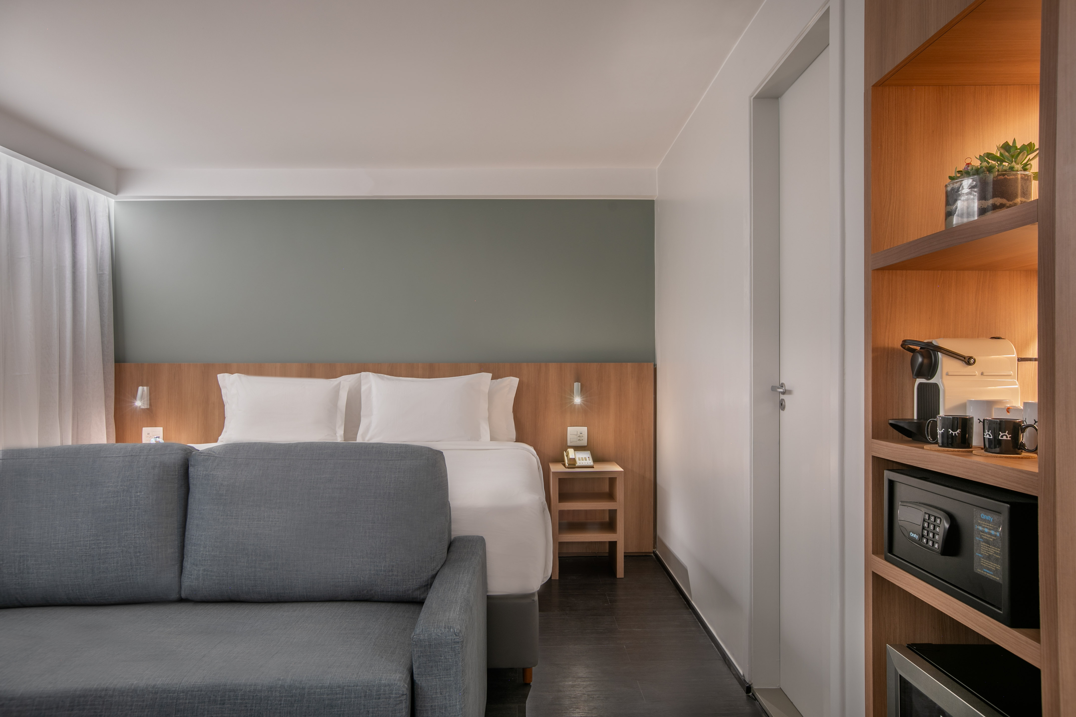 Modern hotel room with bed, gray sofa, coffee machine, and built-in safe. - The Loft for Families - INNSiDE São Paulo Higienópolis, Sao Paulo