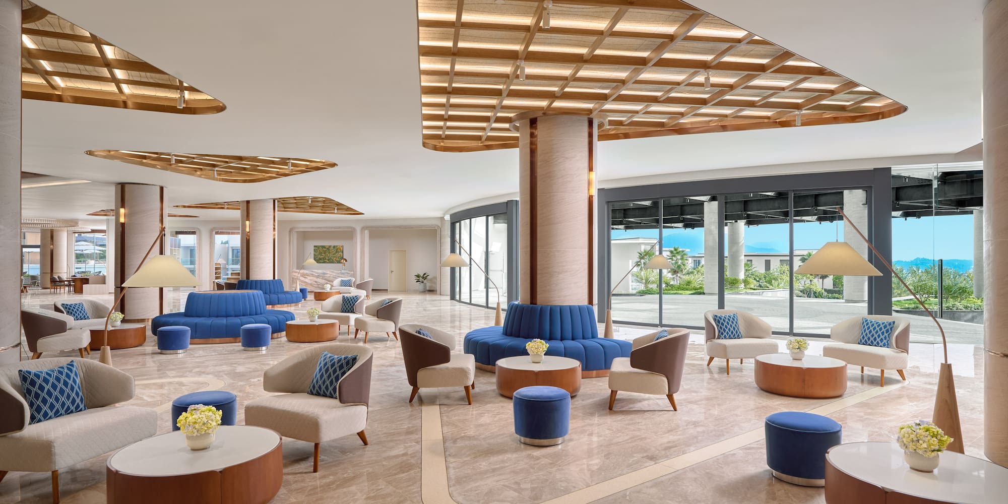 Bright, modern resort lobby with blue sofas, armchairs, and large windows.