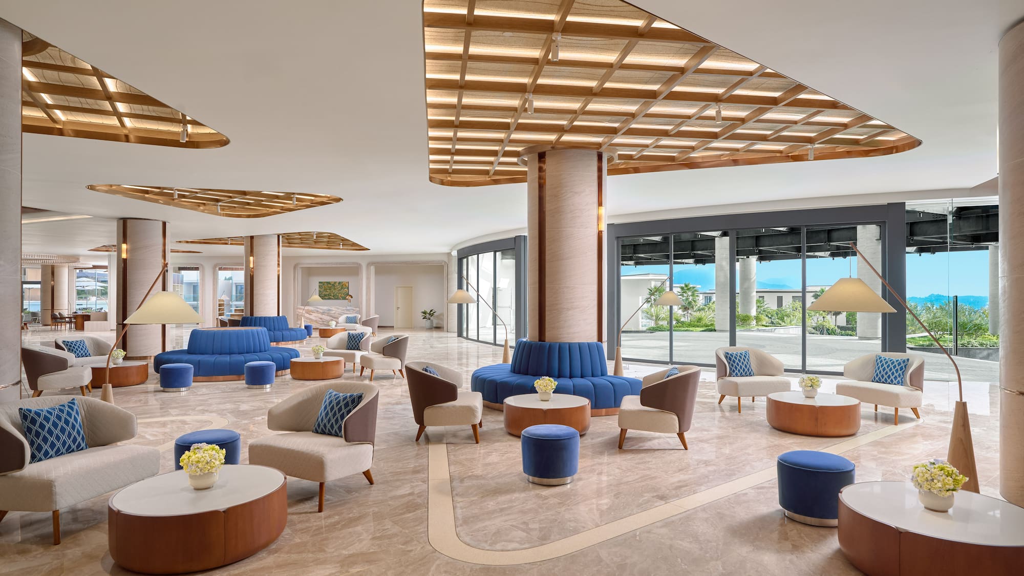 Bright, modern resort lobby with blue sofas, armchairs, and large windows.