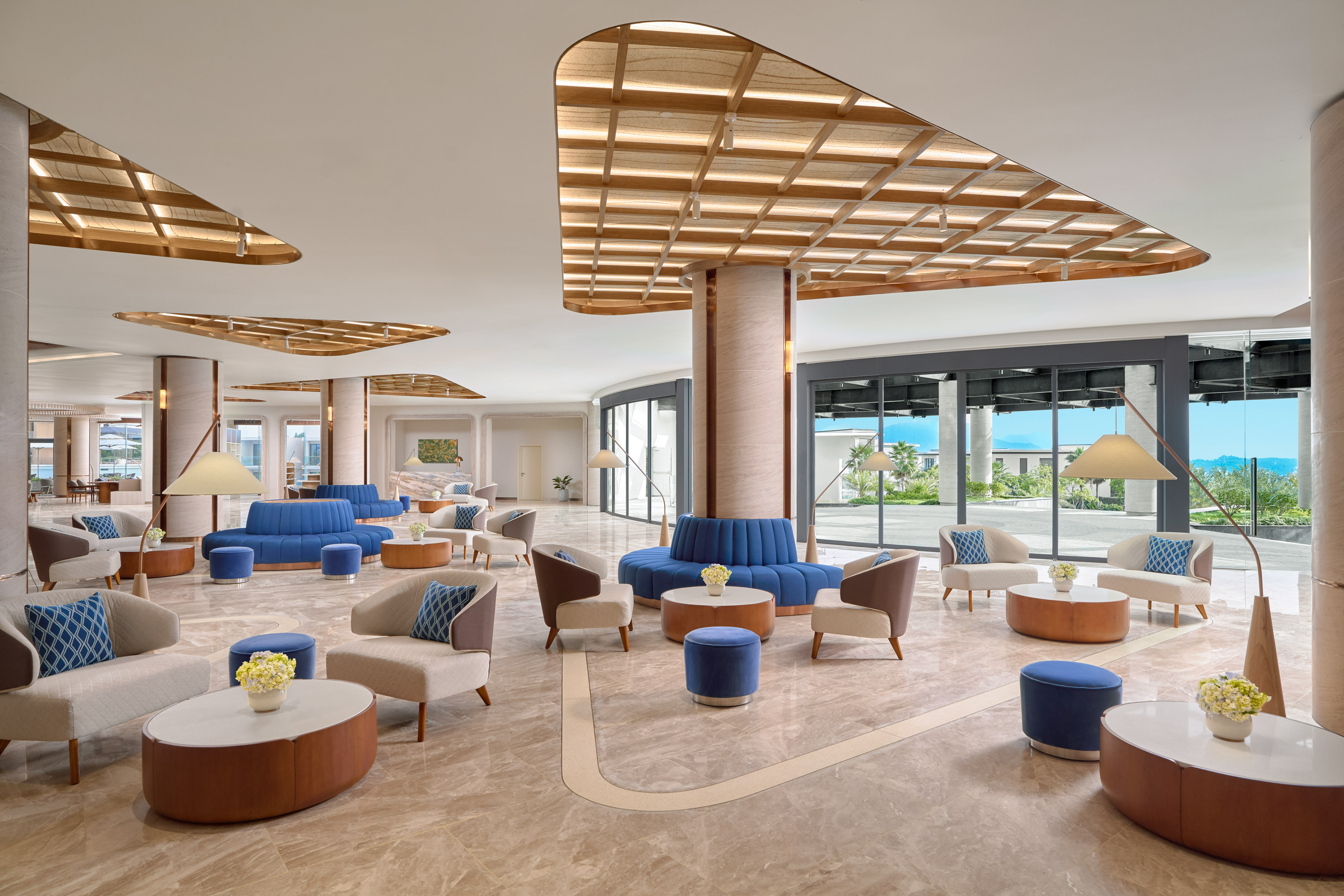 Bright, modern resort lobby with blue sofas, armchairs, and large windows.
