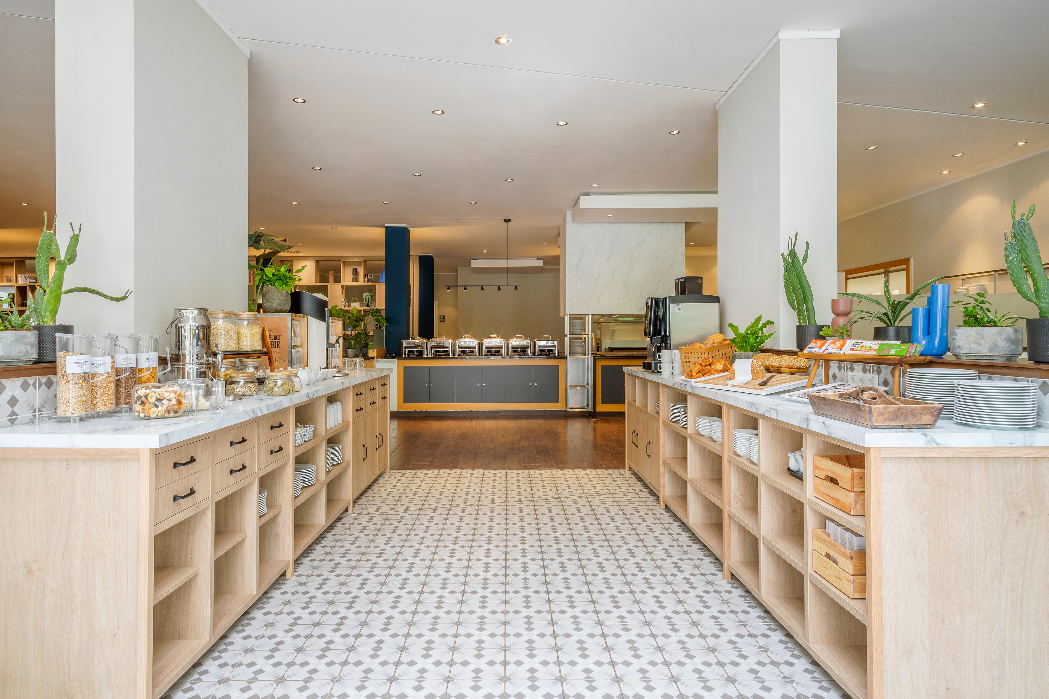Hotel breakfast buffet featuring cereals, fresh pastries, and hot food stations.