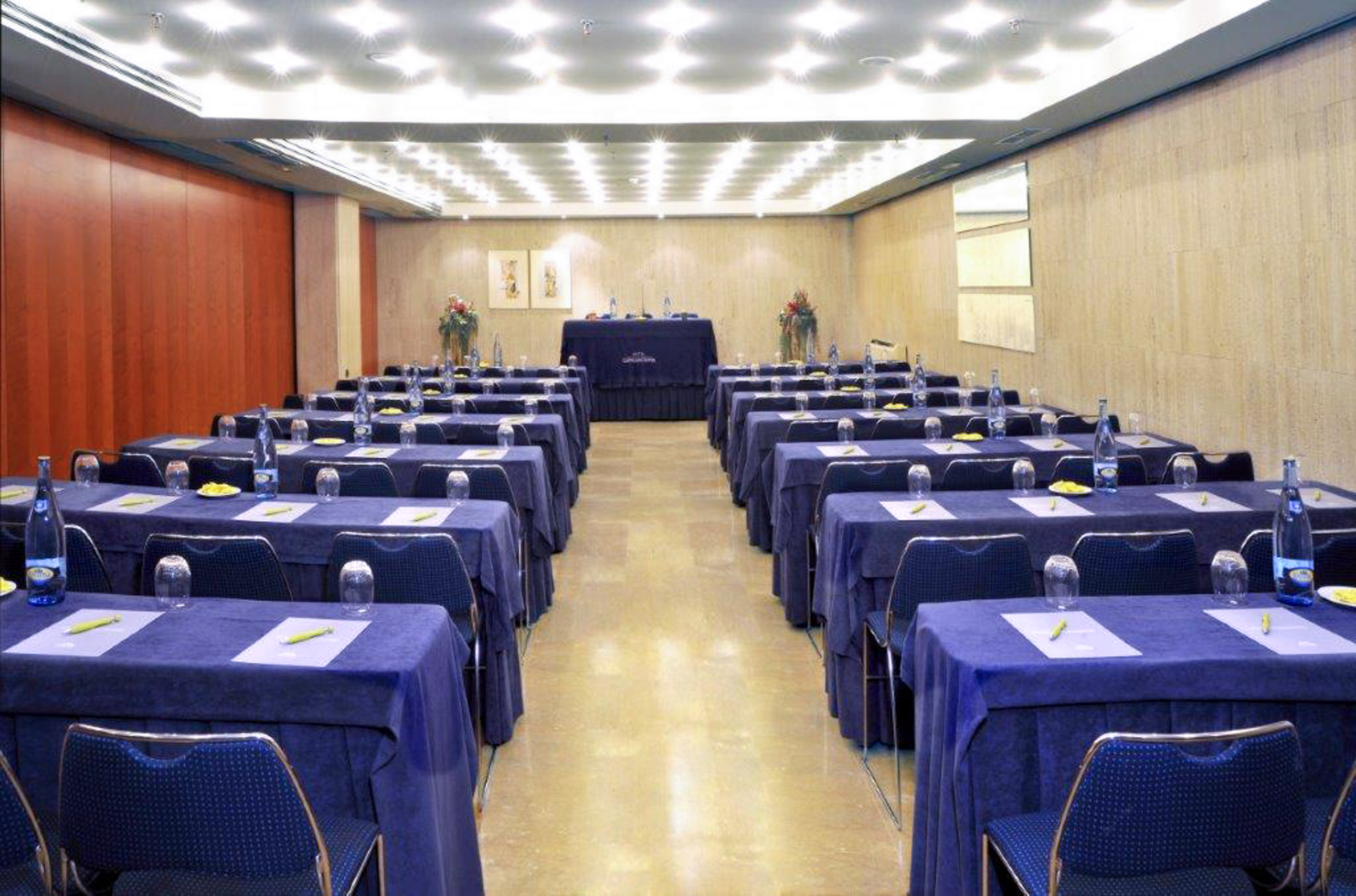 Conference room set for meeting, blue tables, chairs, water, notepads.