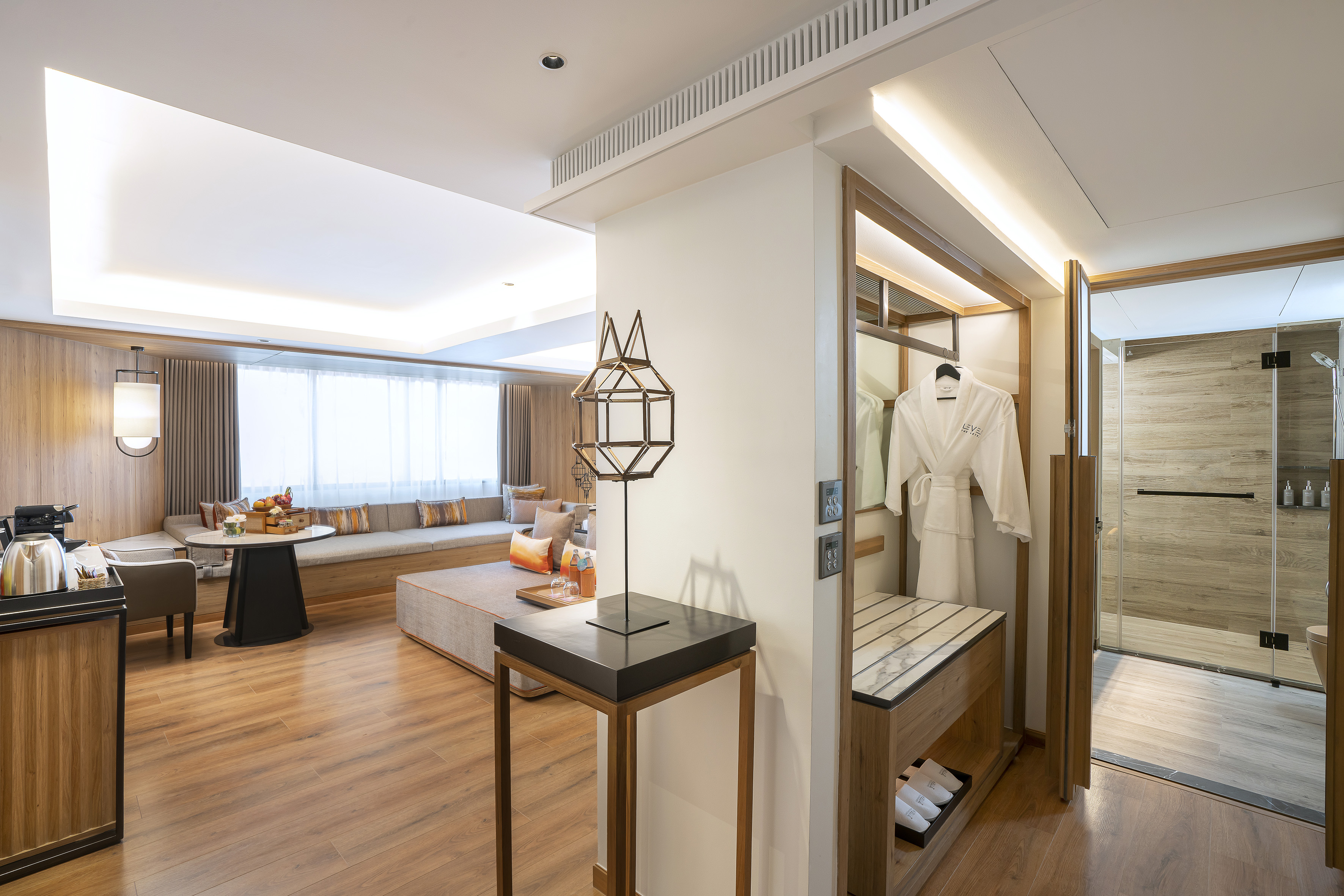 Modern hotel suite, living area, wood floor, walk-in closet, glass shower.