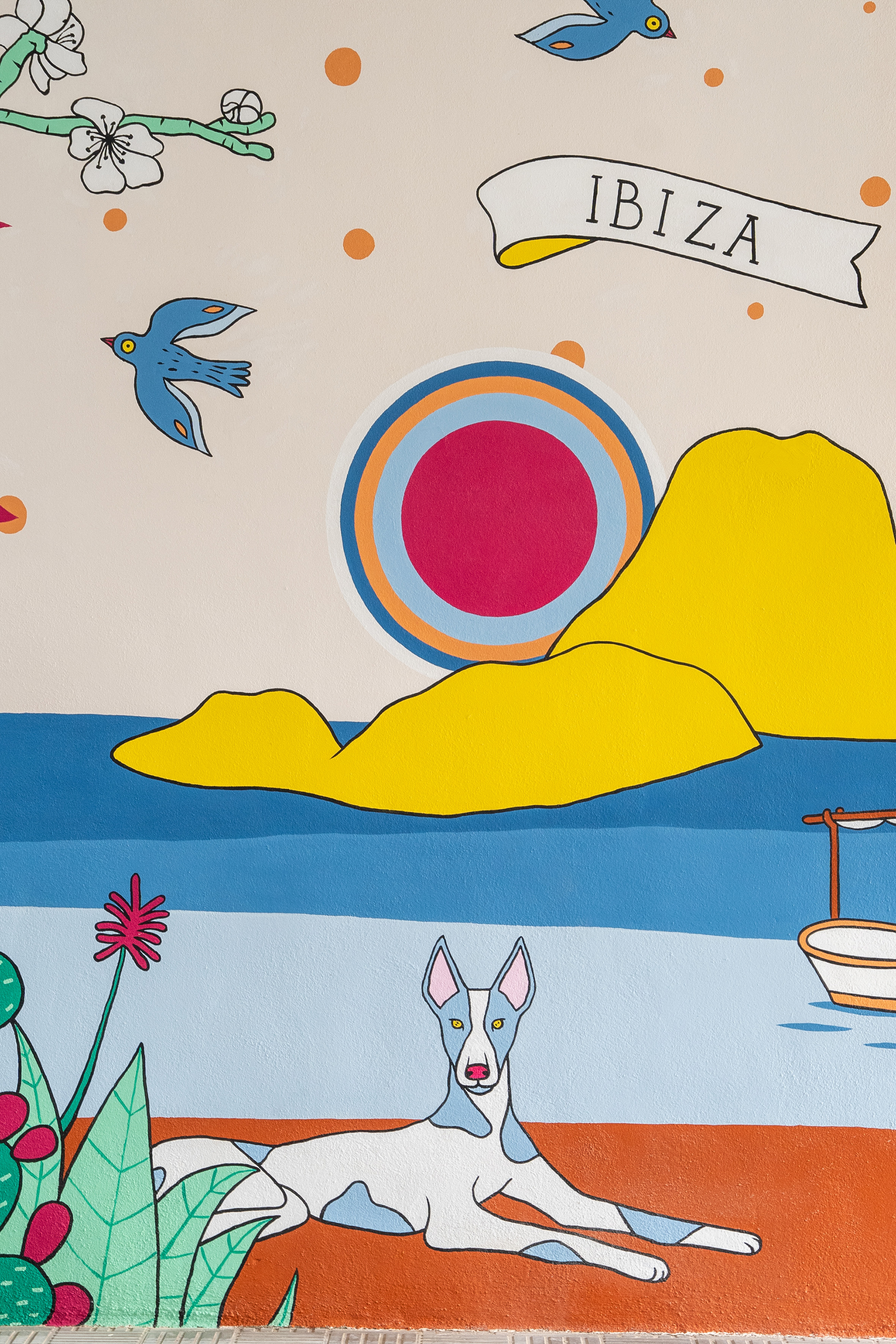 Colorful Ibiza mural: blue birds, yellow mountains, sun, boat, Ibizan Hound.