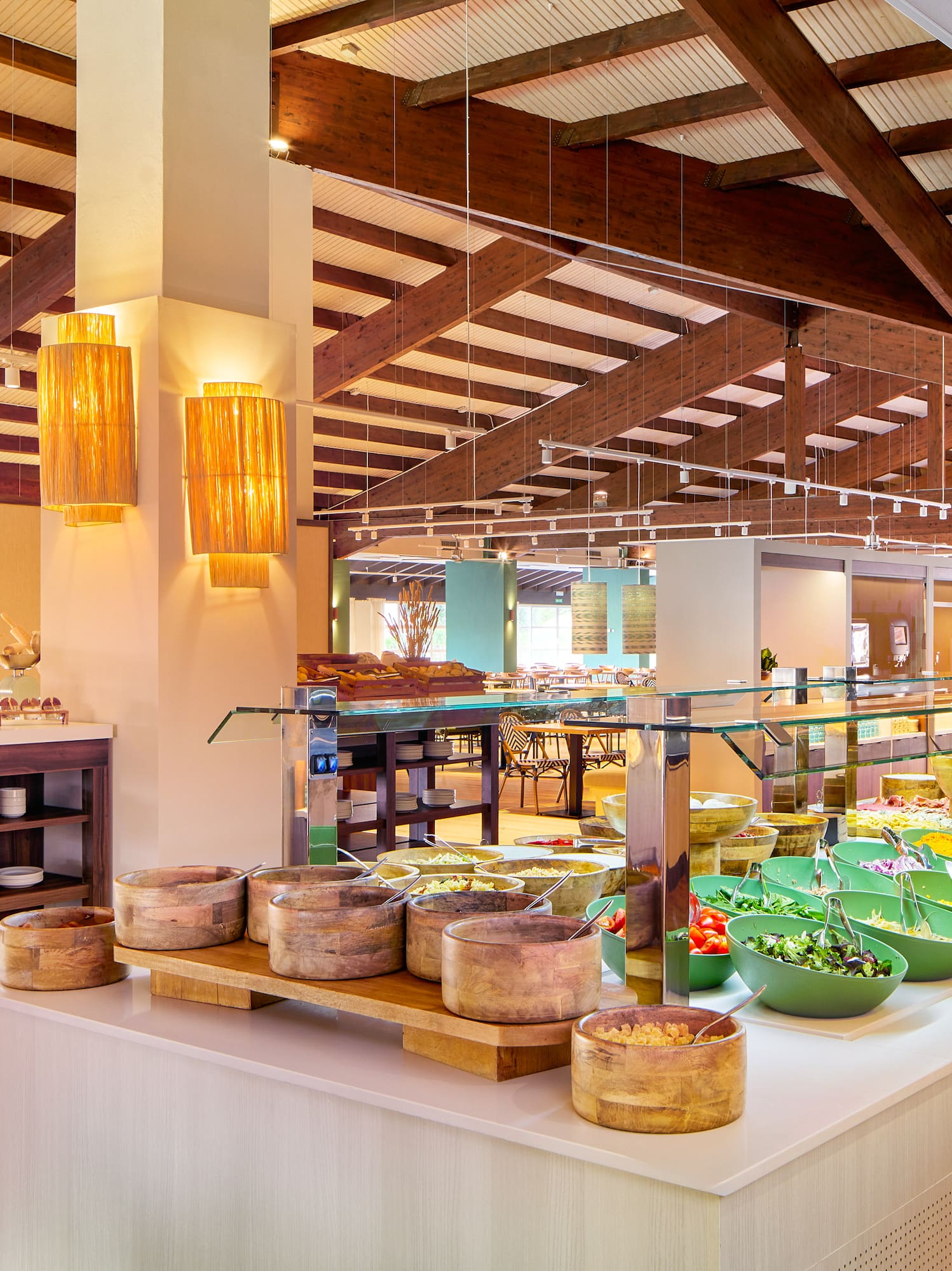 Modern buffet and fresh salad bar with wooden beam ceiling.