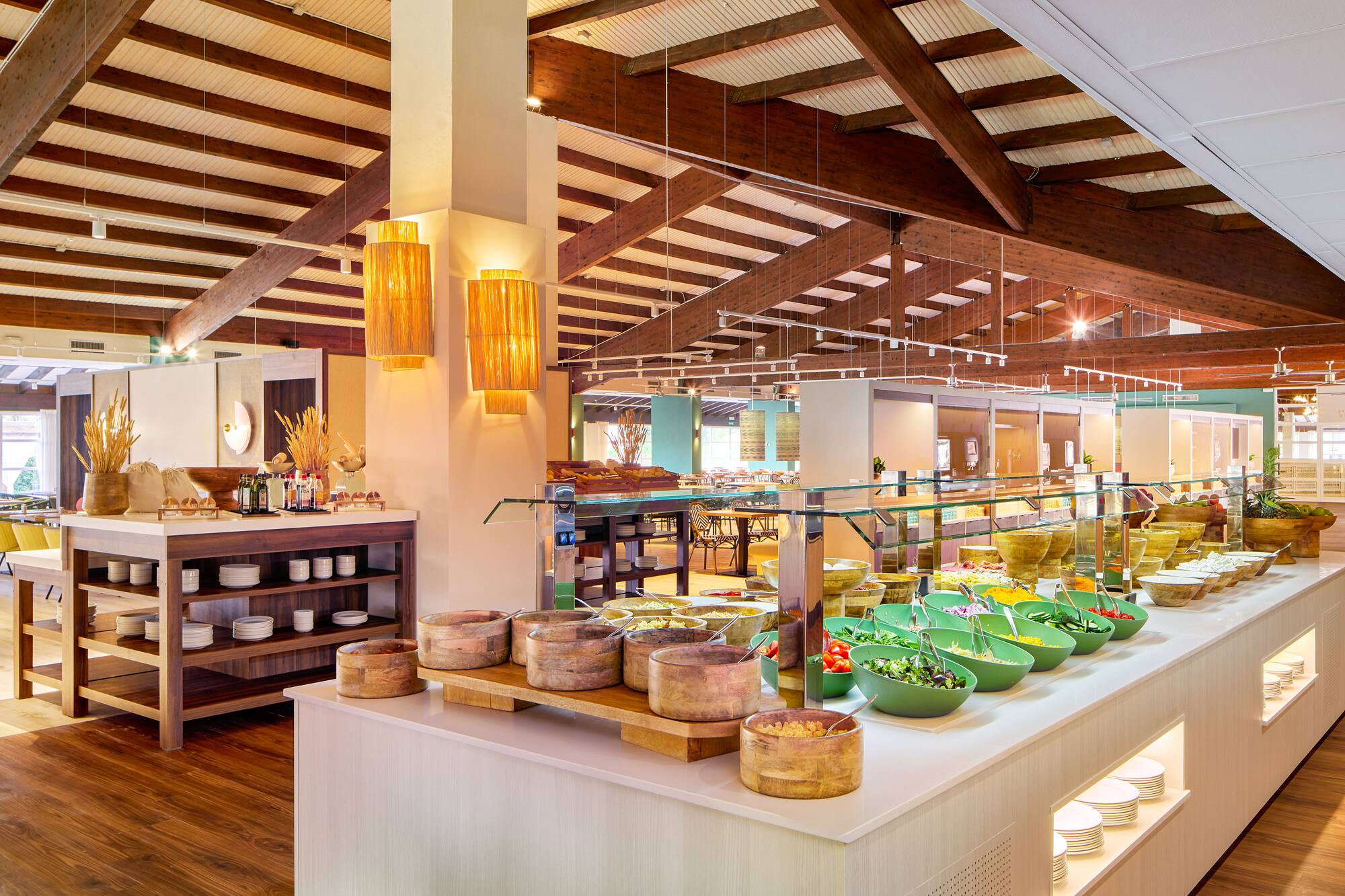 Hotel restaurant buffet with fresh salad bar, diverse food, and wood-beamed ceiling.