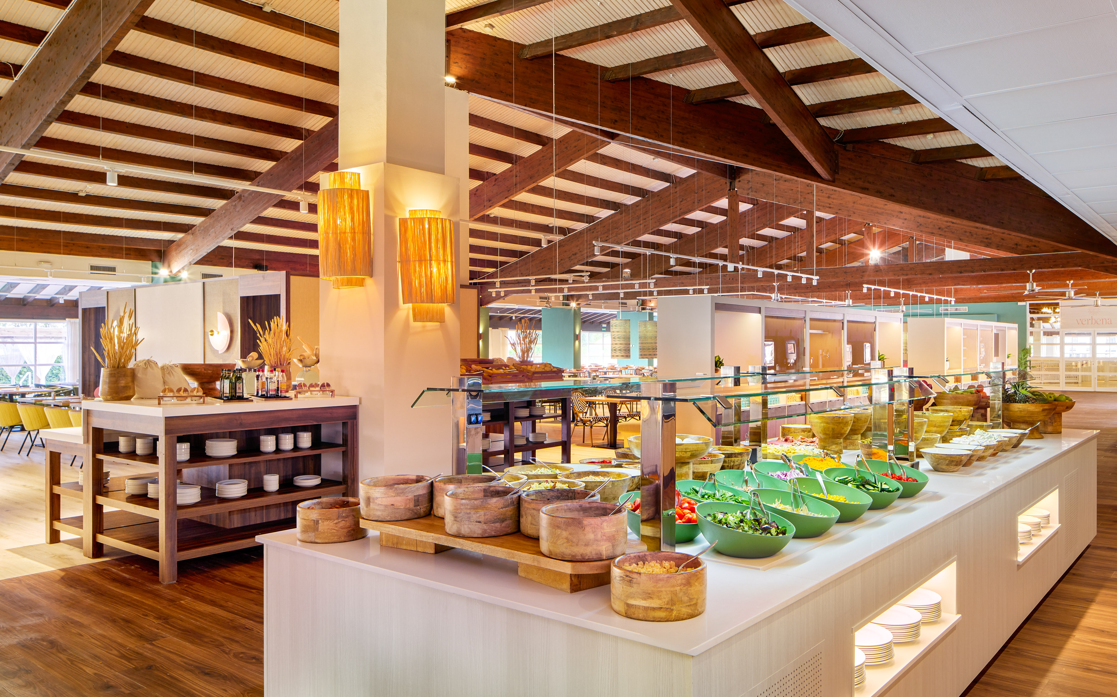 Hotel restaurant buffet with fresh salad bar, diverse food, and wood-beamed ceiling.