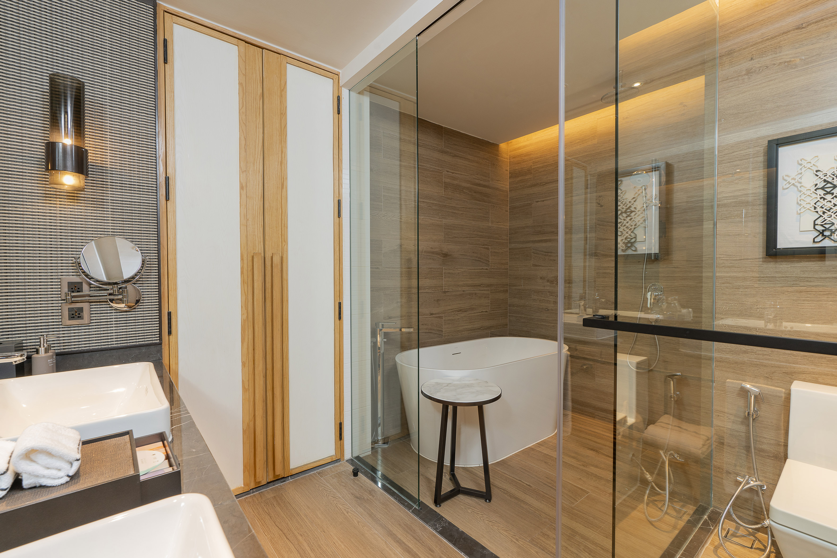 Modern hotel bathroom with double vanity, glass shower, and freestanding tub.