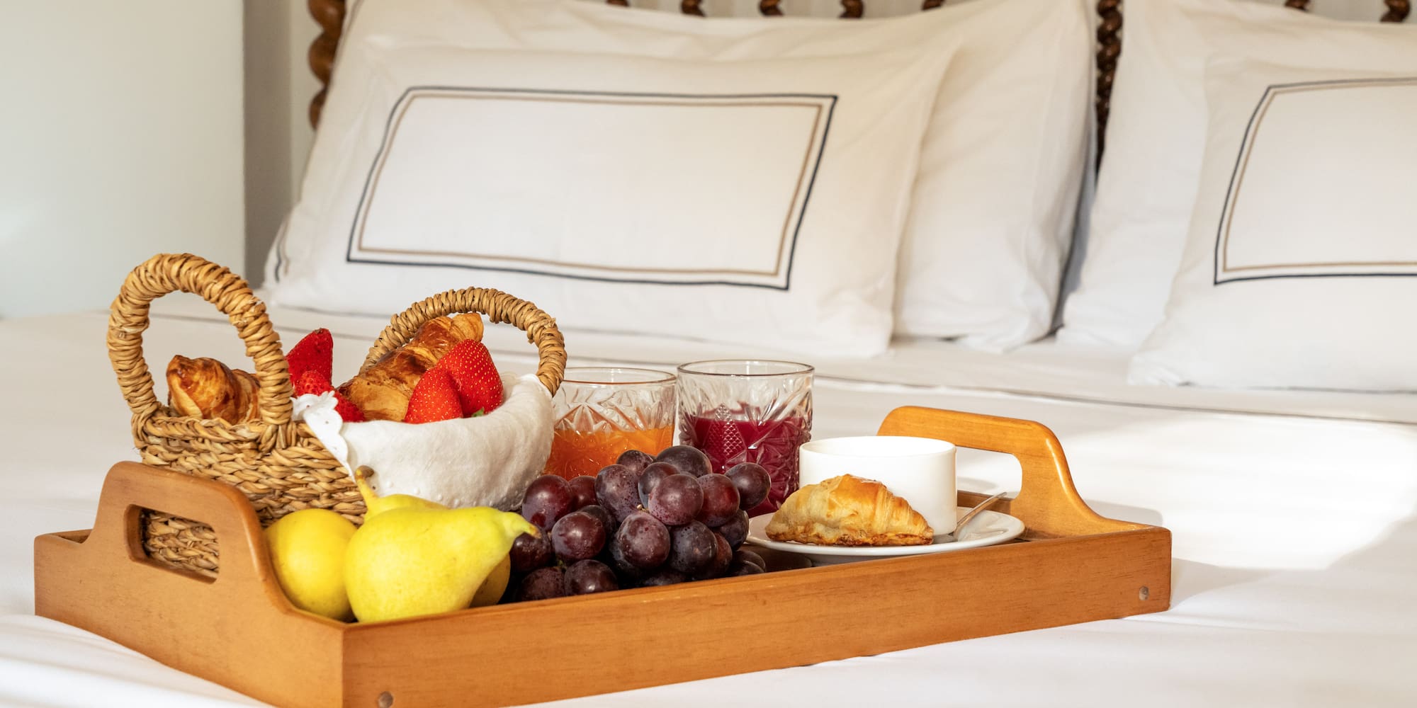 a tray of fruit and juice on a bed