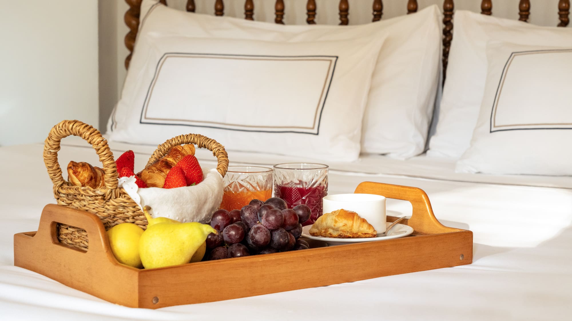 a tray of fruit and juice on a bed