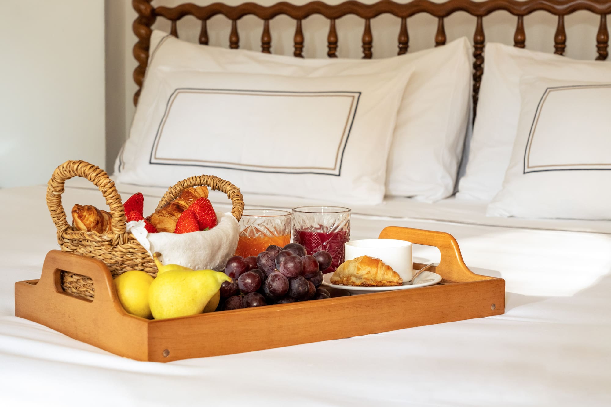 a tray of fruit and juice on a bed