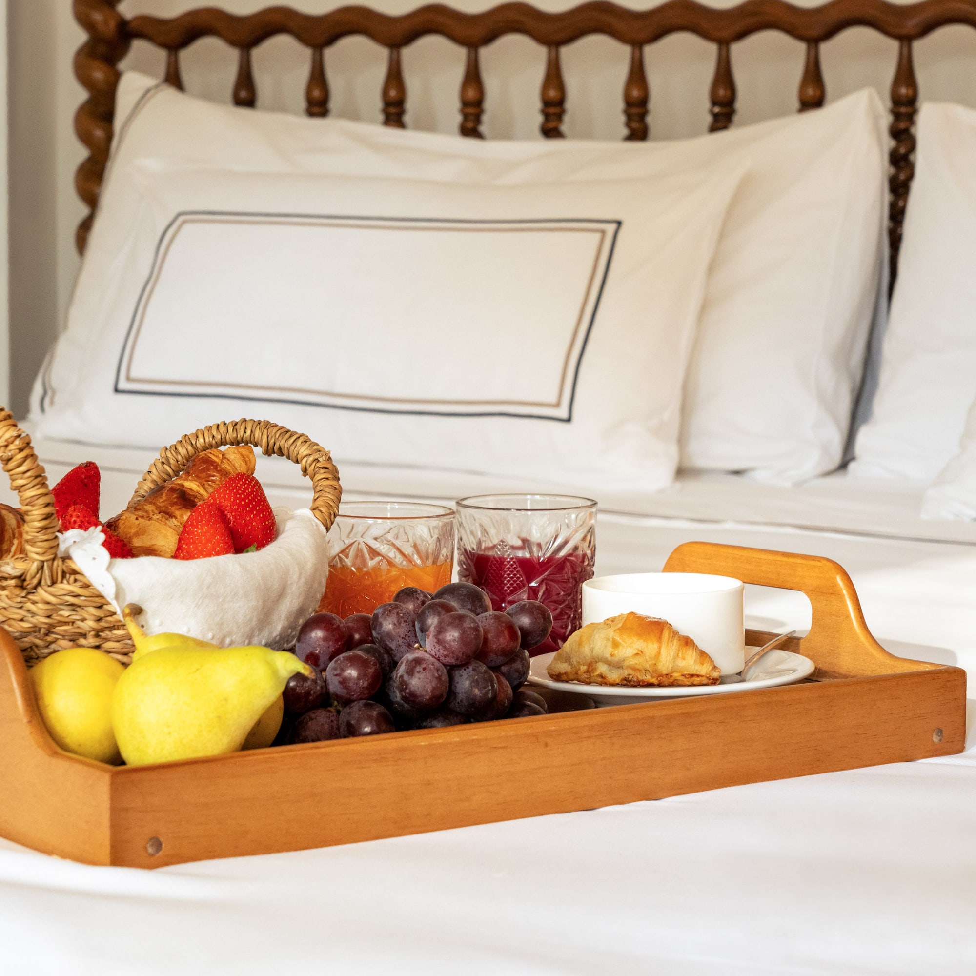 a tray of fruit and juice on a bed