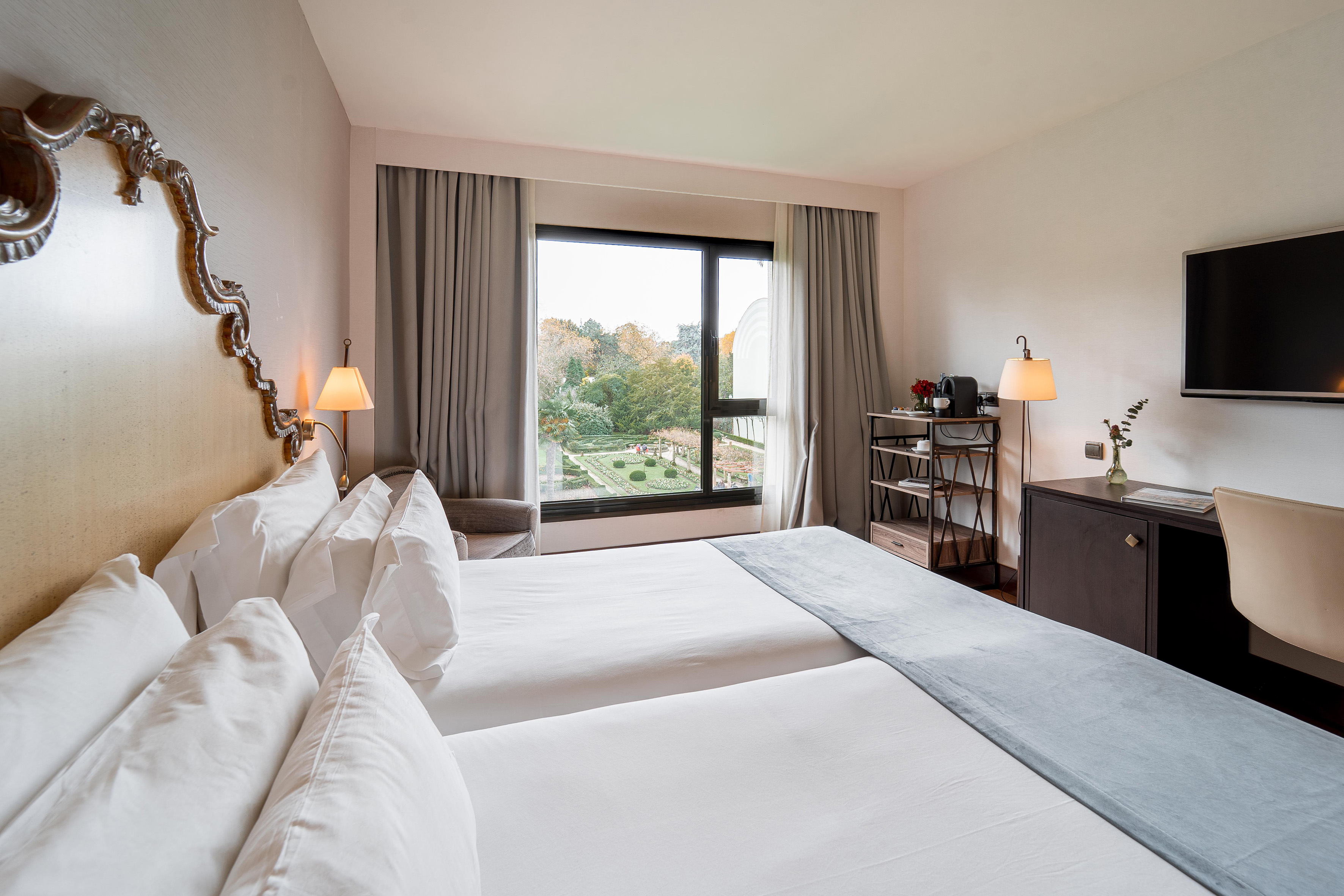 Twin hotel room with garden view, white beds, and elegant decor.