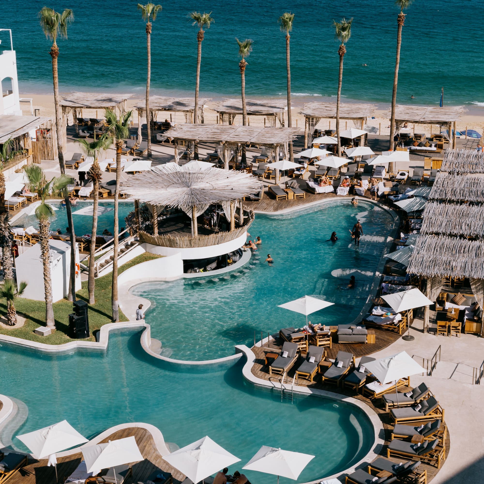 a swimming pool with umbrellas and chairs on a beach