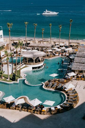a swimming pool with umbrellas and chairs on a beach