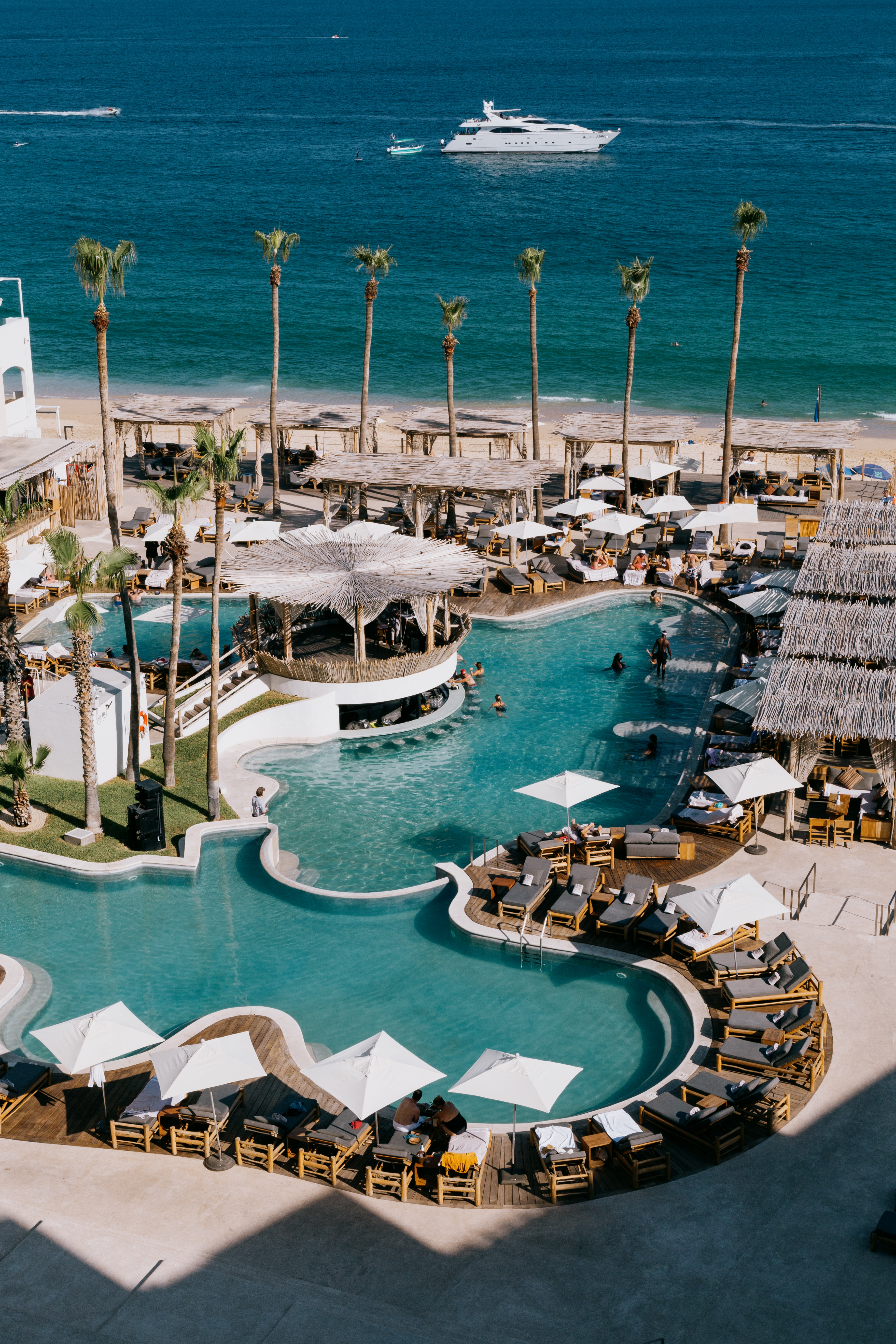 a swimming pool with umbrellas and chairs on a beach