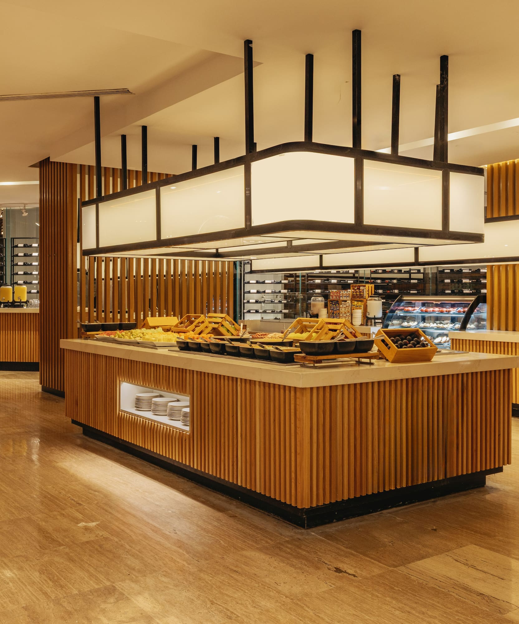Modern hotel buffet with diverse food on wooden counters, warm lighting.