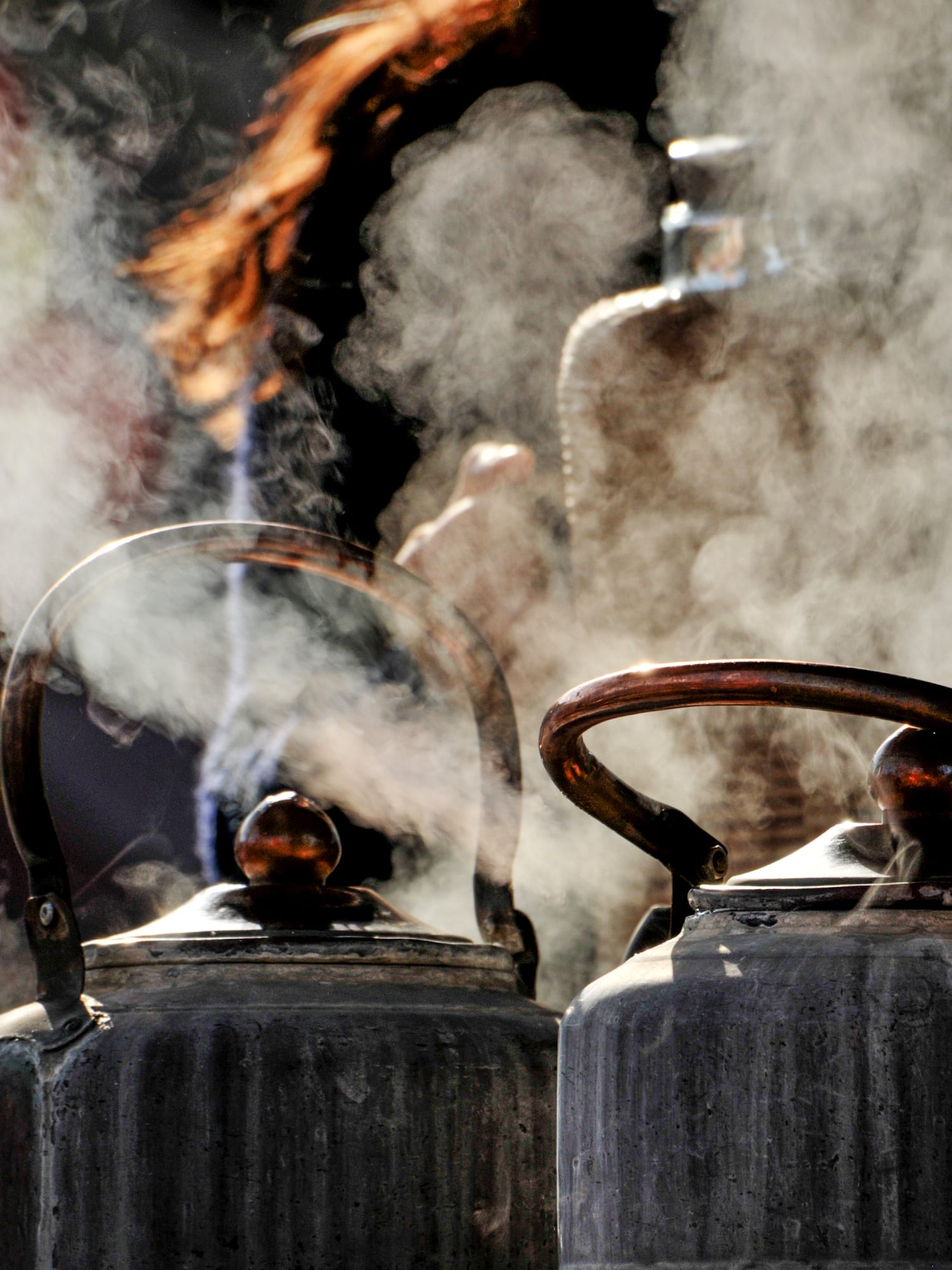 a group of metal kettles with steam coming out of them