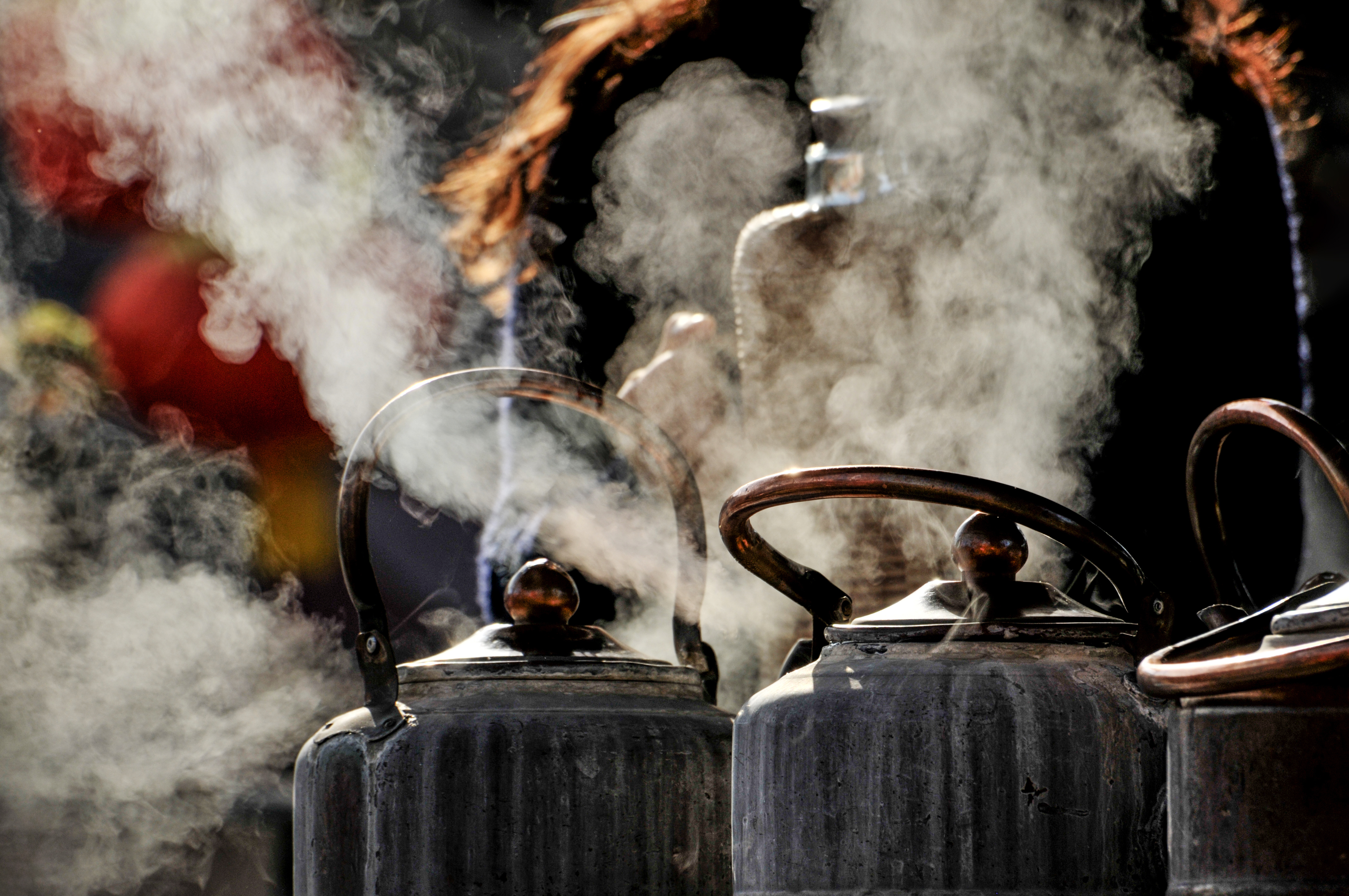 a group of metal kettles with steam coming out of them