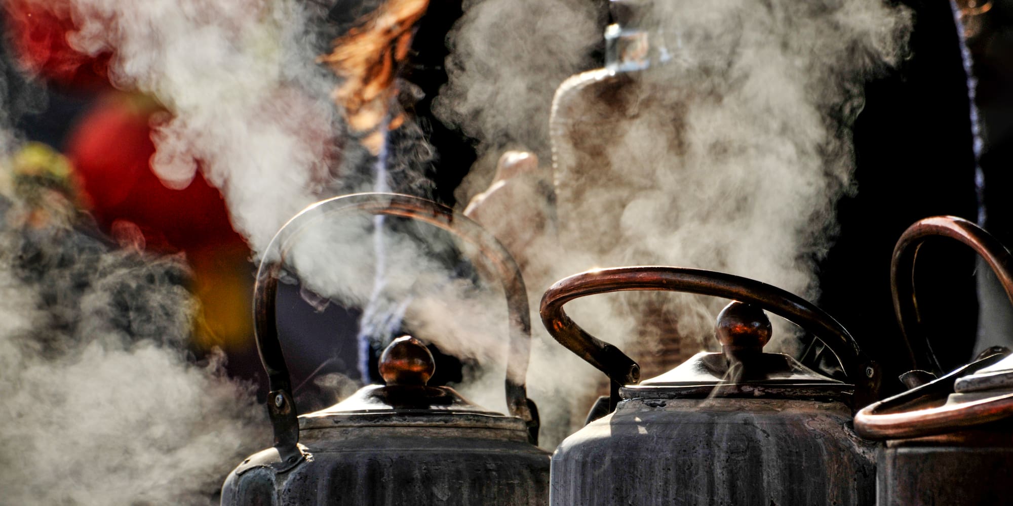 a group of metal kettles with steam coming out of them
