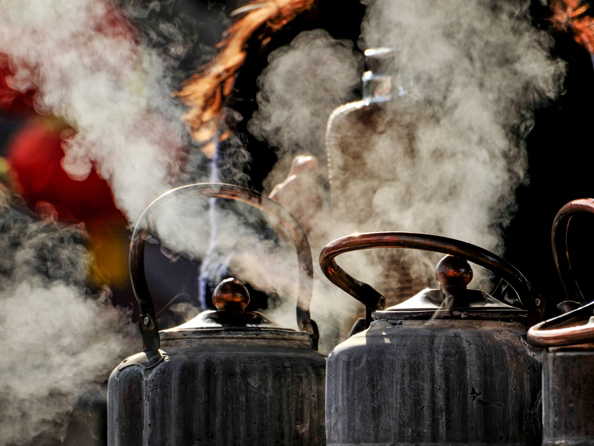 a group of metal kettles with steam coming out of them