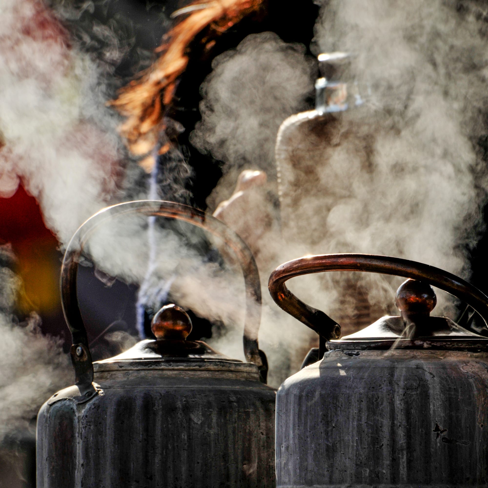 a group of metal kettles with steam coming out of them