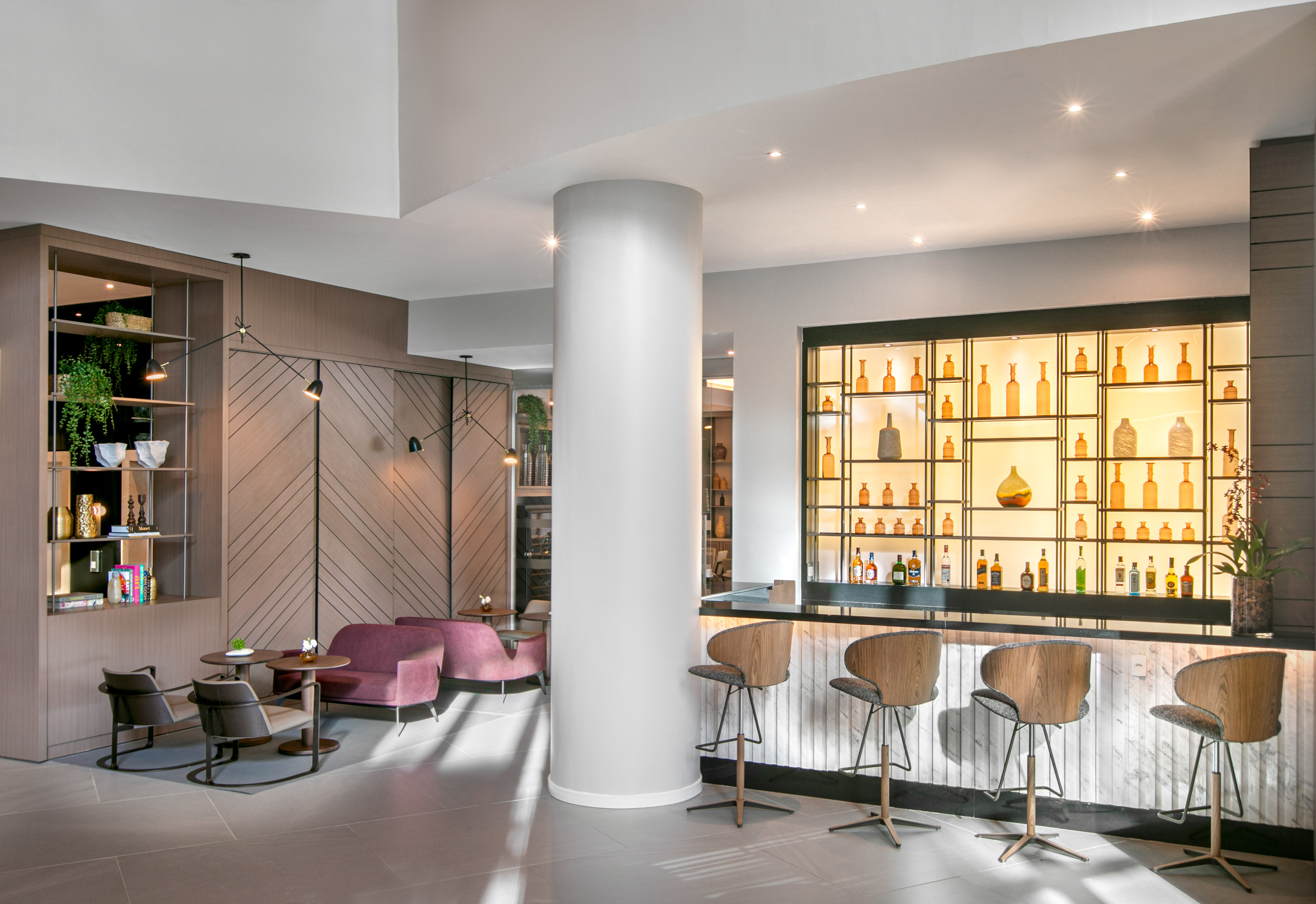 Modern hotel bar and lounge area with stylish seating and illuminated bottle display.