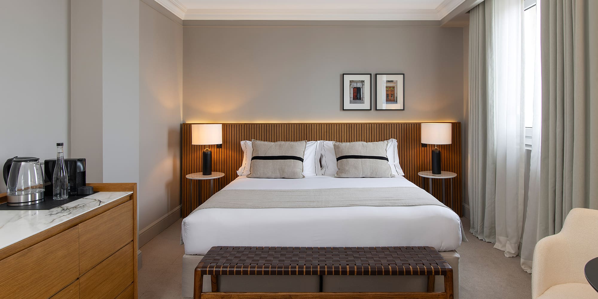 a bed with a bench and lamps in a room