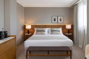a bed with a bench and lamps in a room