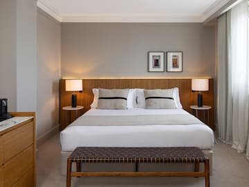 a bed with a bench and lamps in a room
