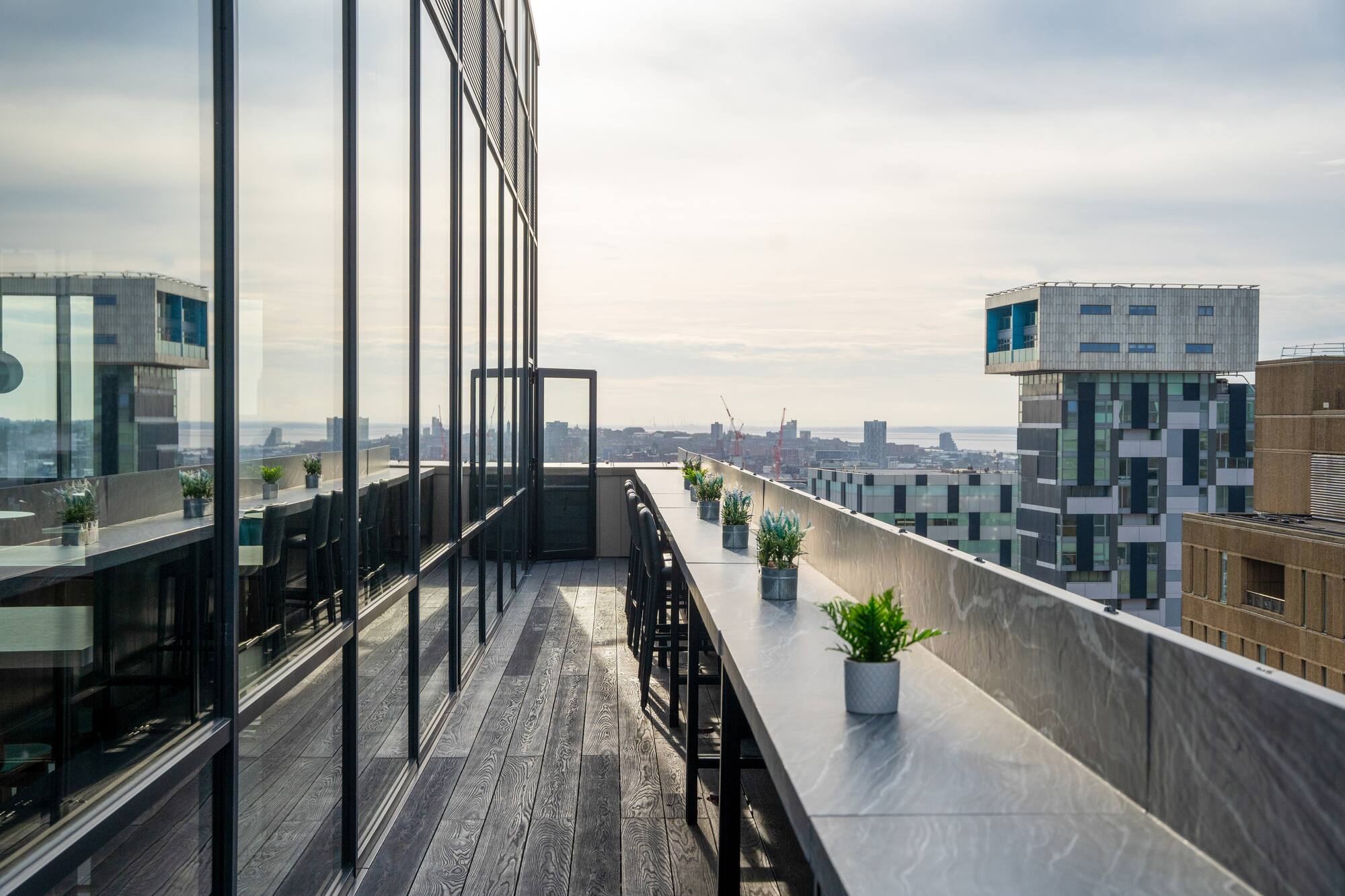 Modern rooftop terrace with city skyline view and outdoor bar seating.