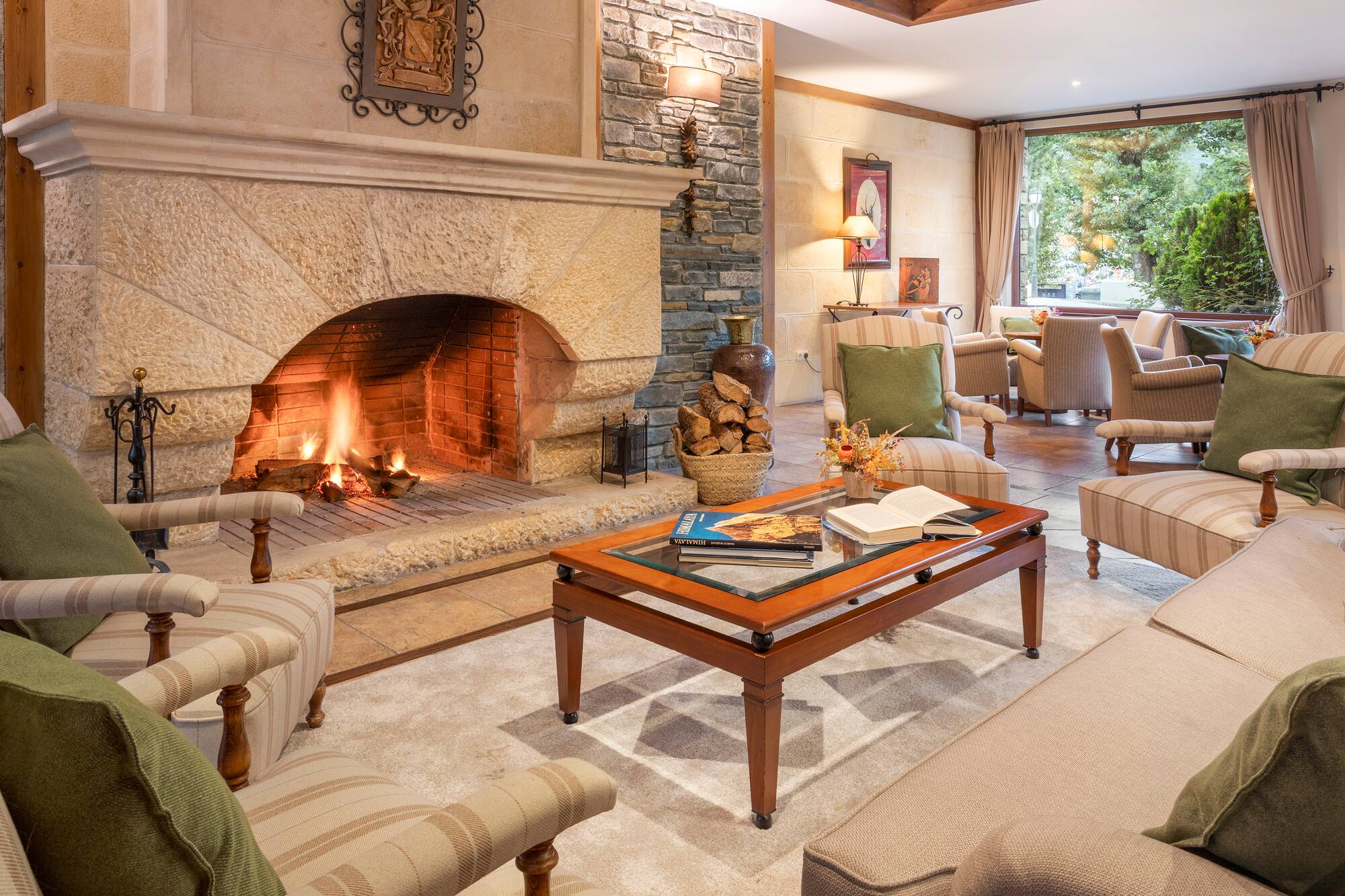 Cozy living room with stone fireplace, comfortable furniture, and nature view.
