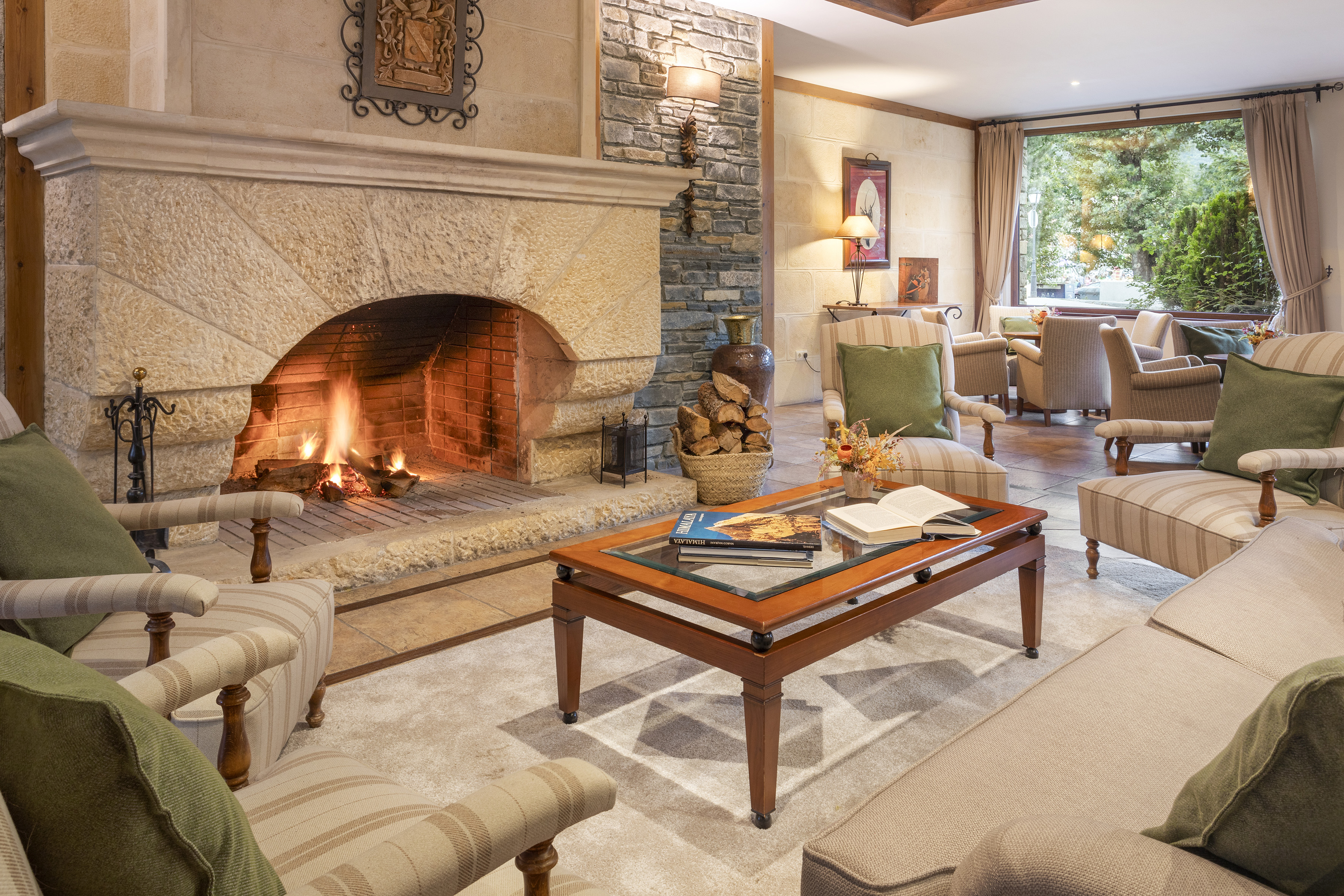 Cozy living room with stone fireplace, comfortable furniture, and nature view.