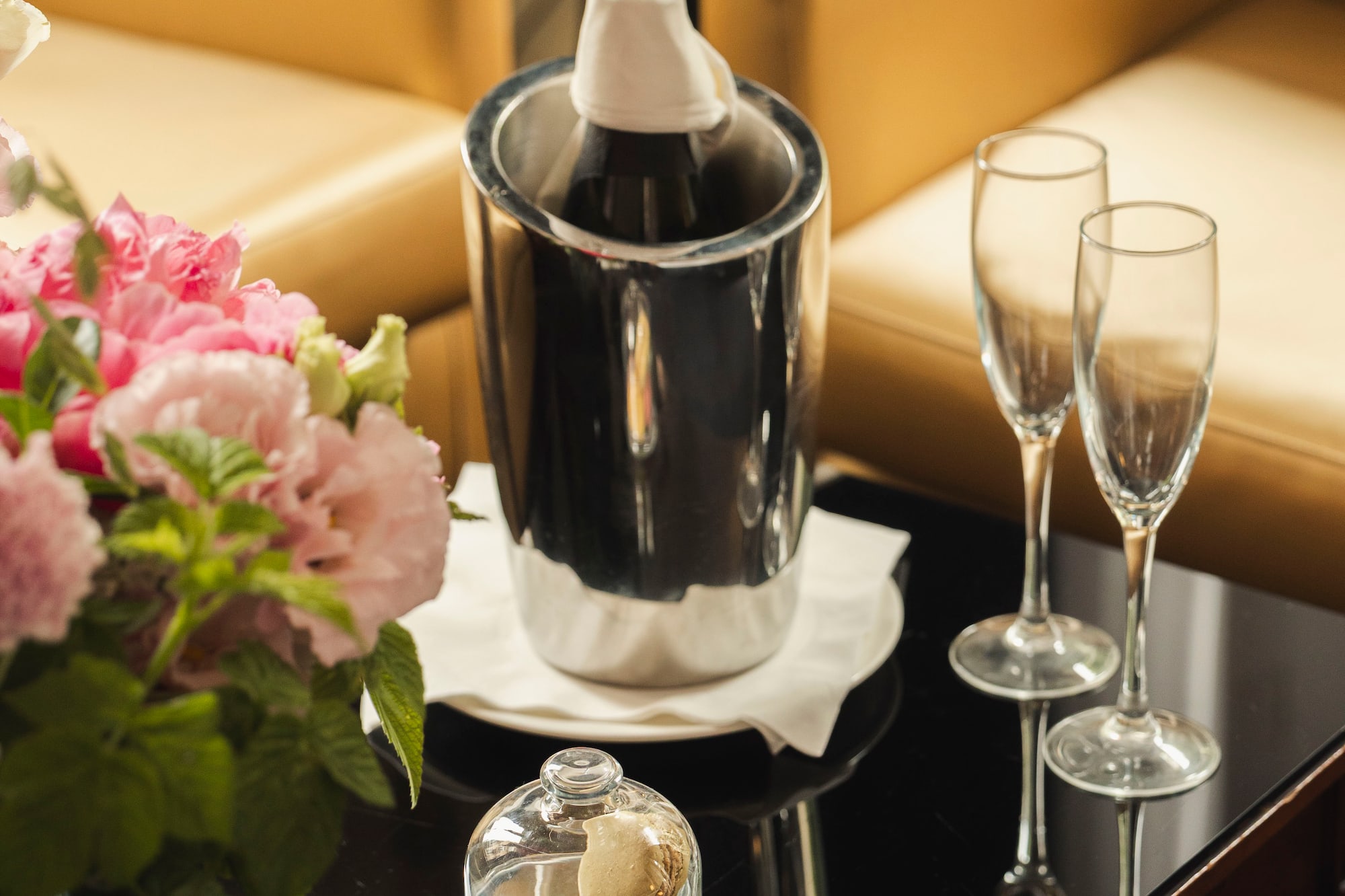 Luxury hotel amenities: champagne, flutes, macarons, and flowers.
