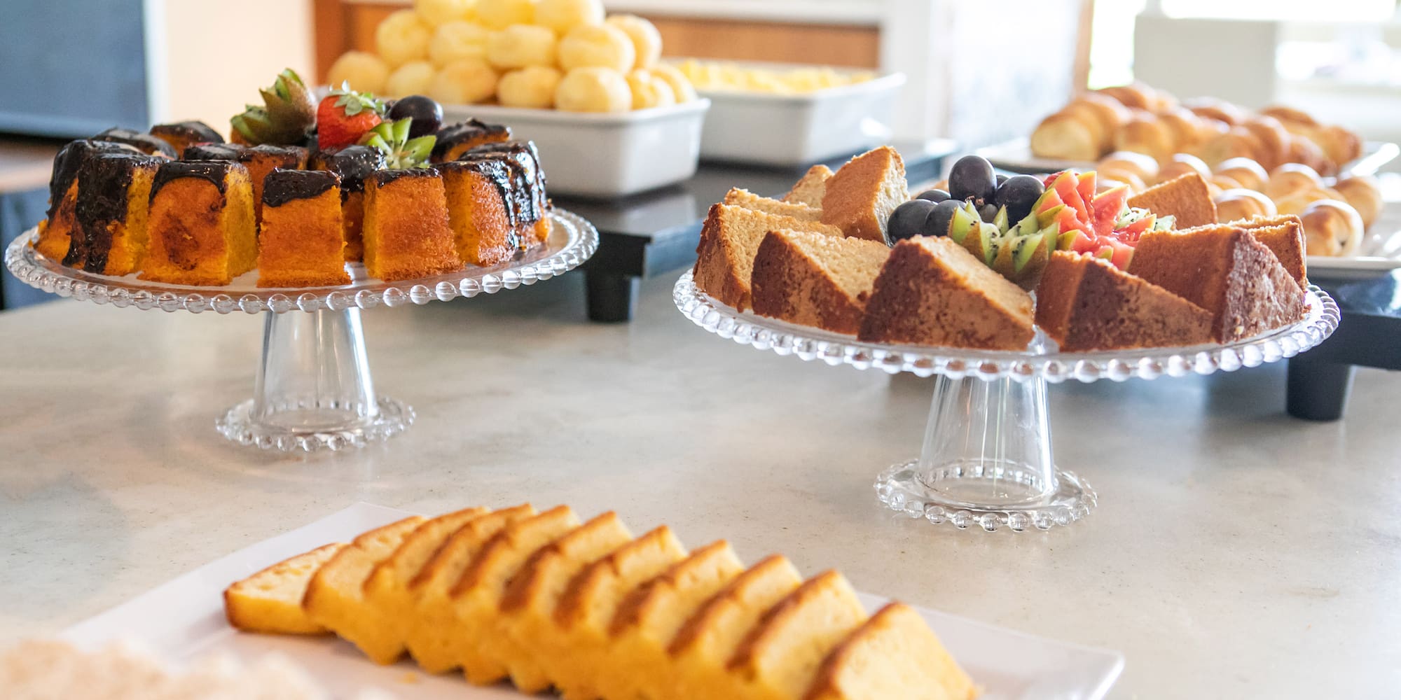 Breakfast buffet featuring assorted cakes, fresh fruit, and pastries.