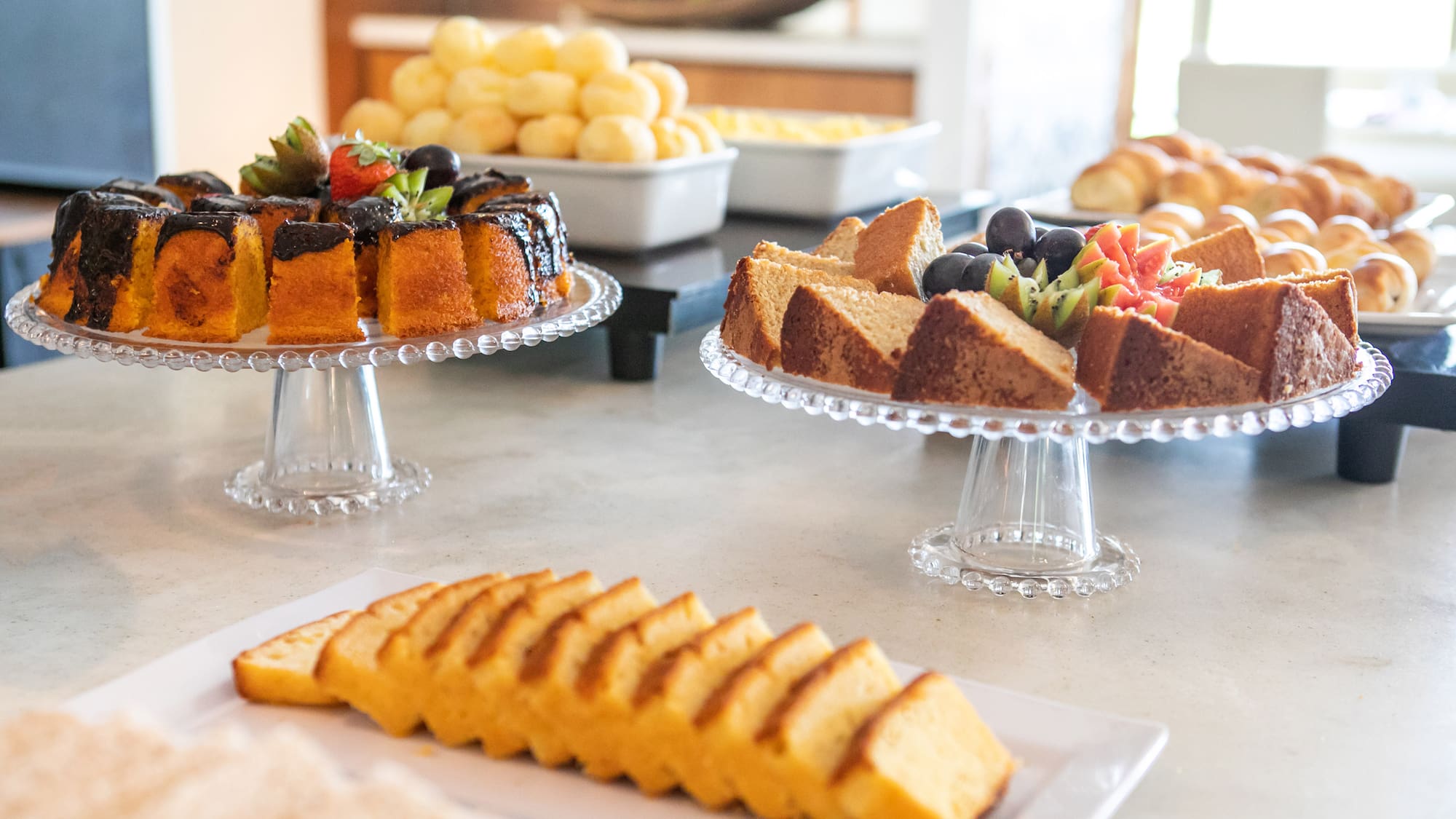 Breakfast buffet featuring assorted cakes, fresh fruit, and pastries.