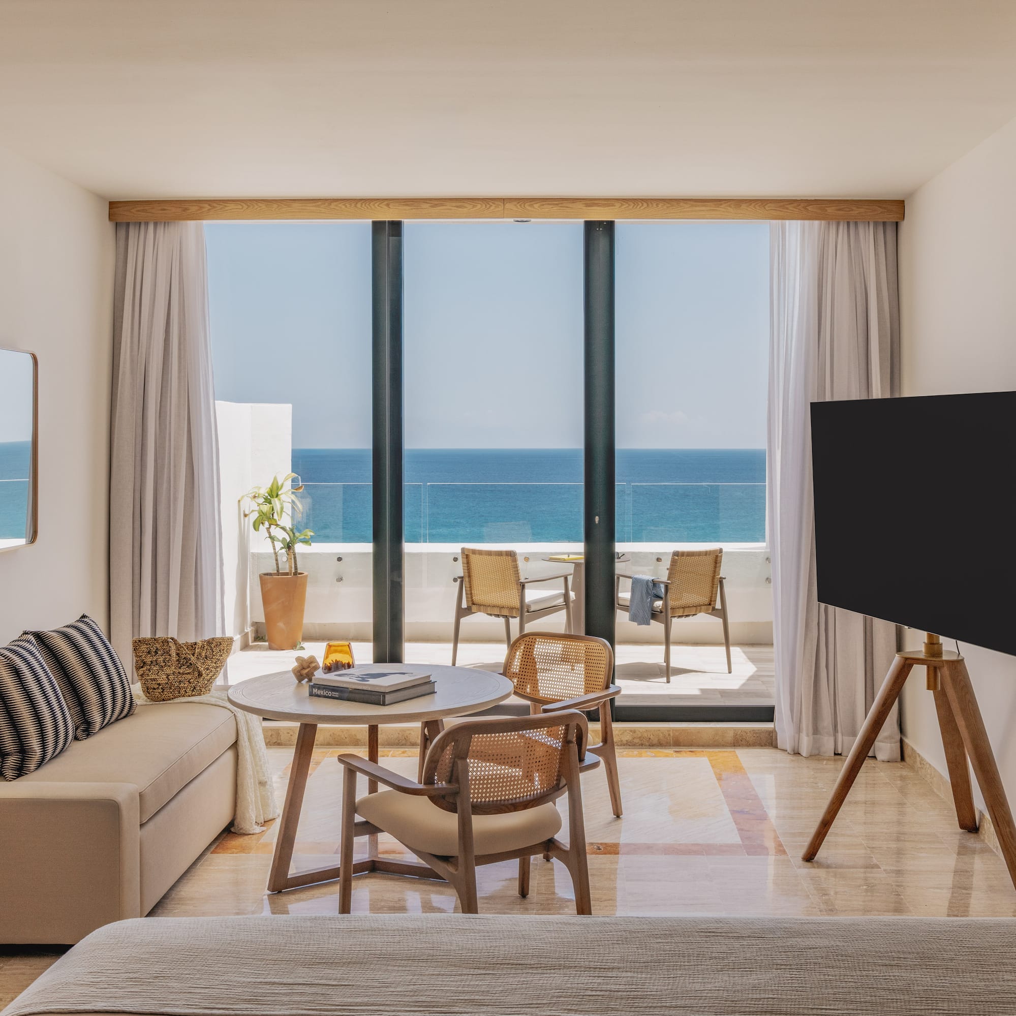 Luxury hotel room with stunning ocean view balcony, sofa, and wood accents.