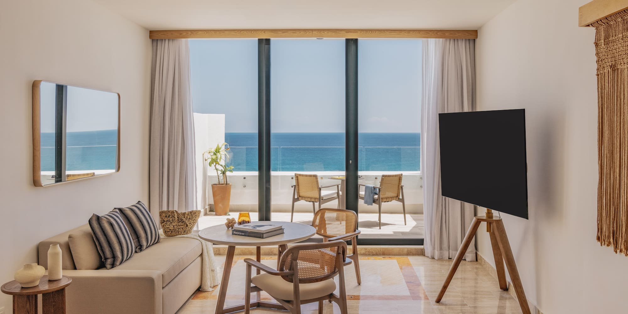 Luxury hotel room with stunning ocean view balcony, sofa, and wood accents.