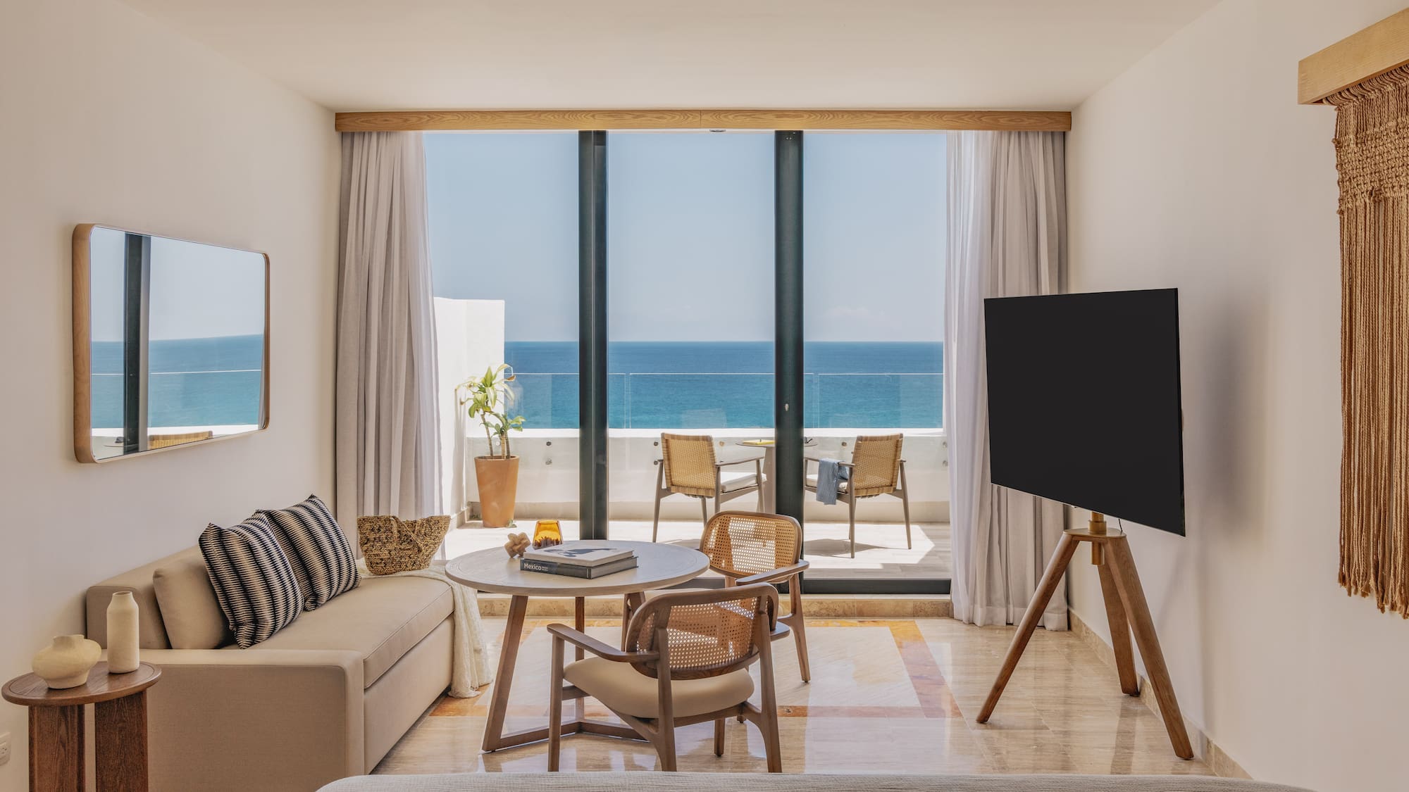 Luxury hotel room with stunning ocean view balcony, sofa, and wood accents.