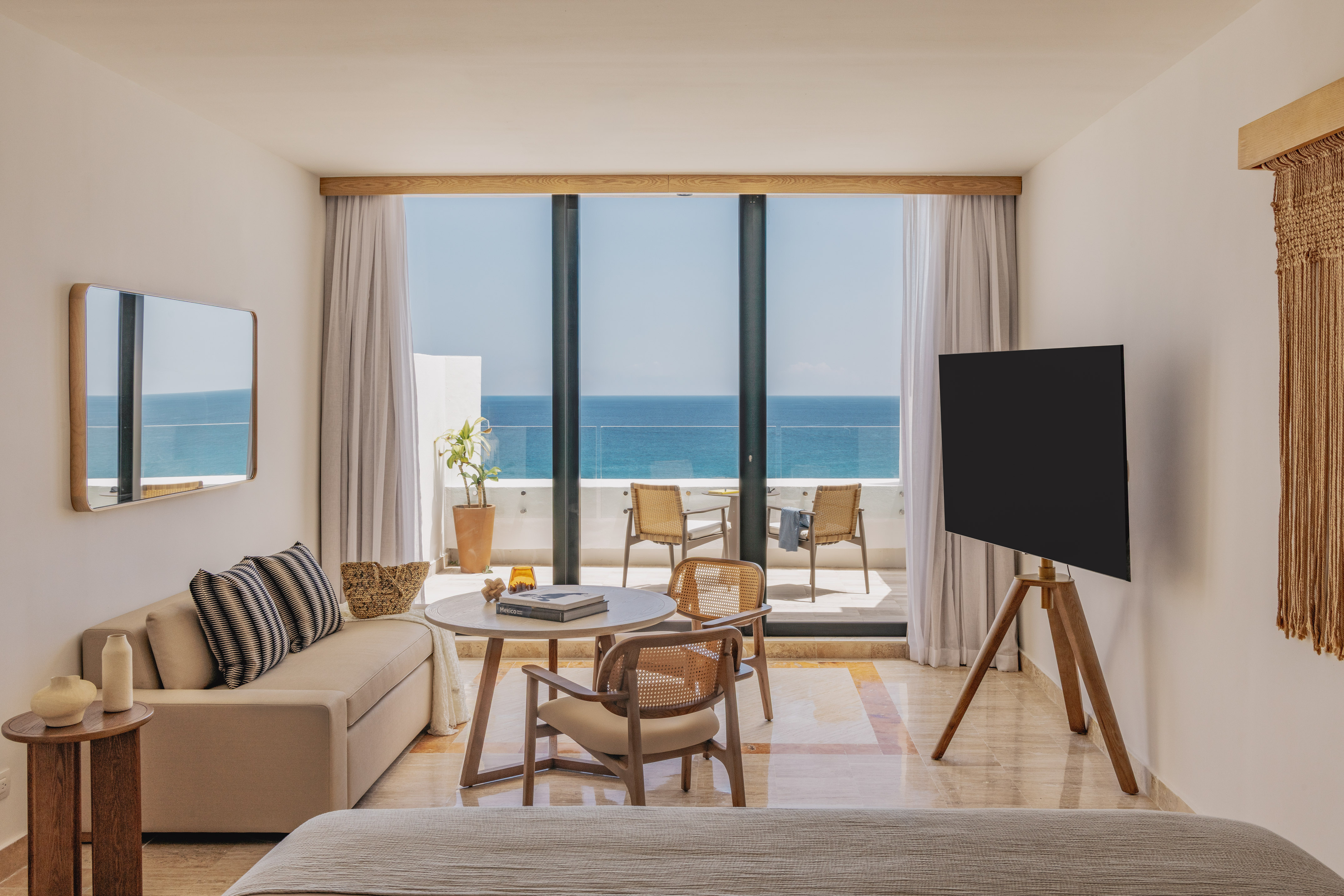 Luxury hotel room with stunning ocean view balcony, sofa, and wood accents.