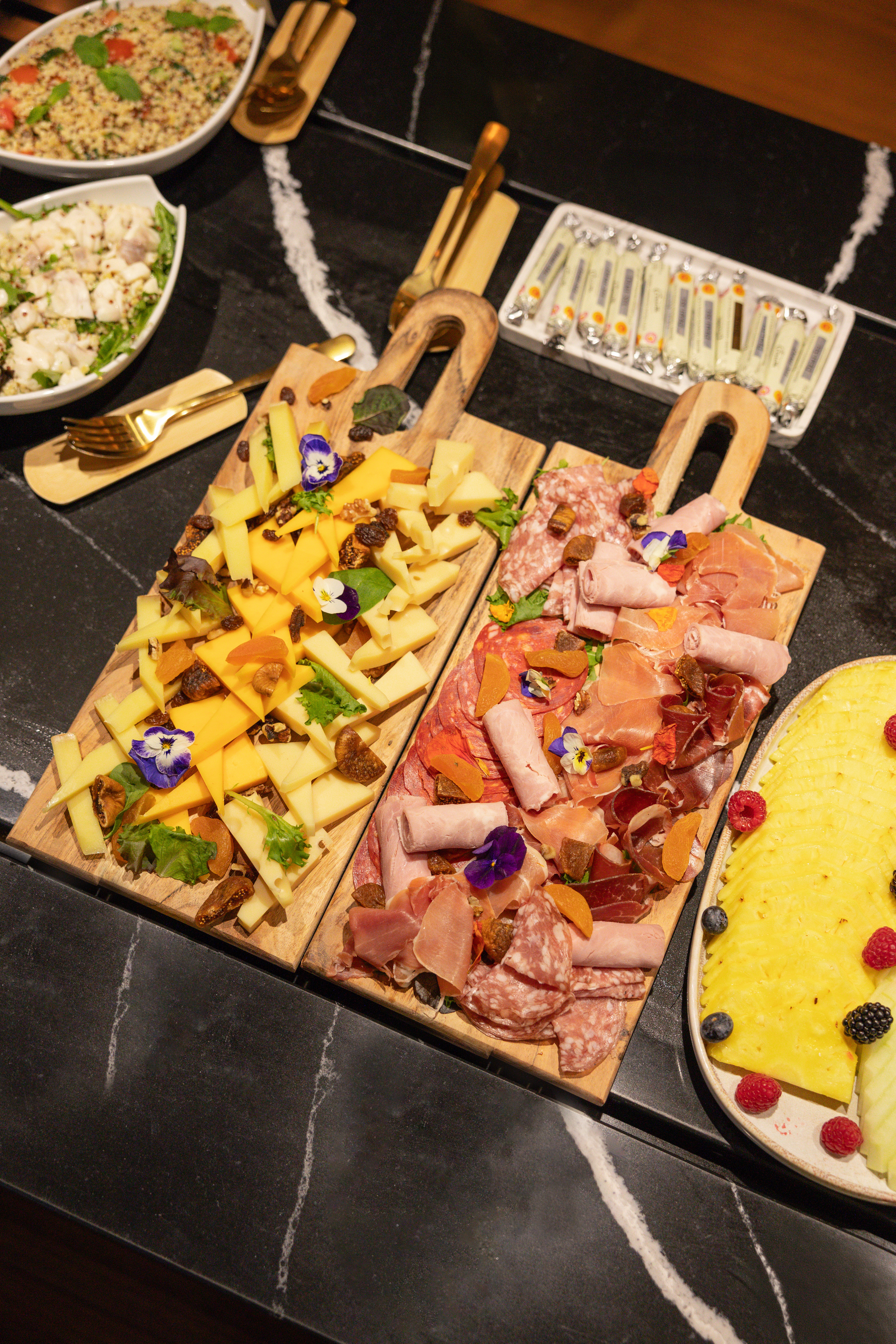 Charcuterie and cheese boards, fruit platter, salads, and butter.