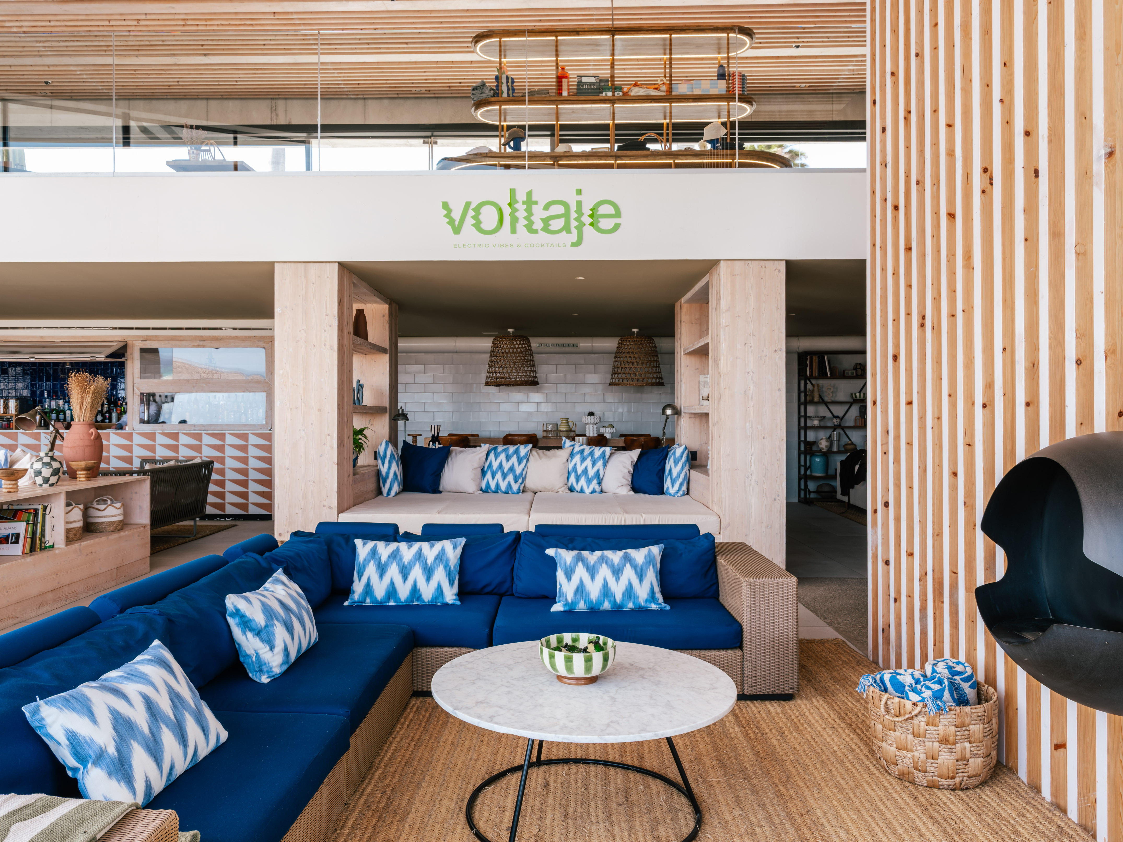 Voltaje lounge: blue sectional sofa, marble table, wood accents, modern design.