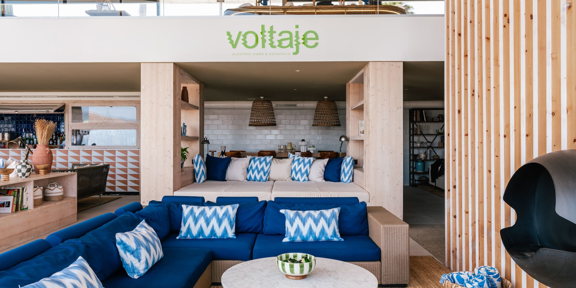 Voltaje lounge: blue sectional sofa, marble table, wood accents, modern design.