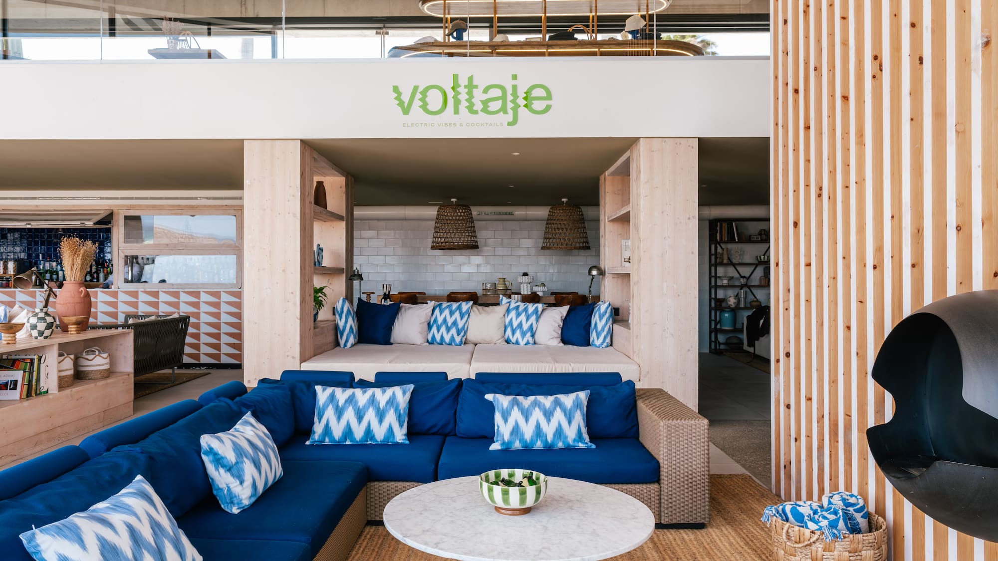 Voltaje lounge: blue sectional sofa, marble table, wood accents, modern design.